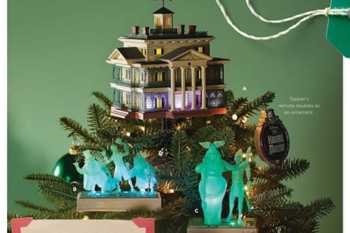 A Christmas tree adorned with a Haunted Mansion ornament as a topper, resembling a creepy house, and surrounded by ghostly figurines on a green background.