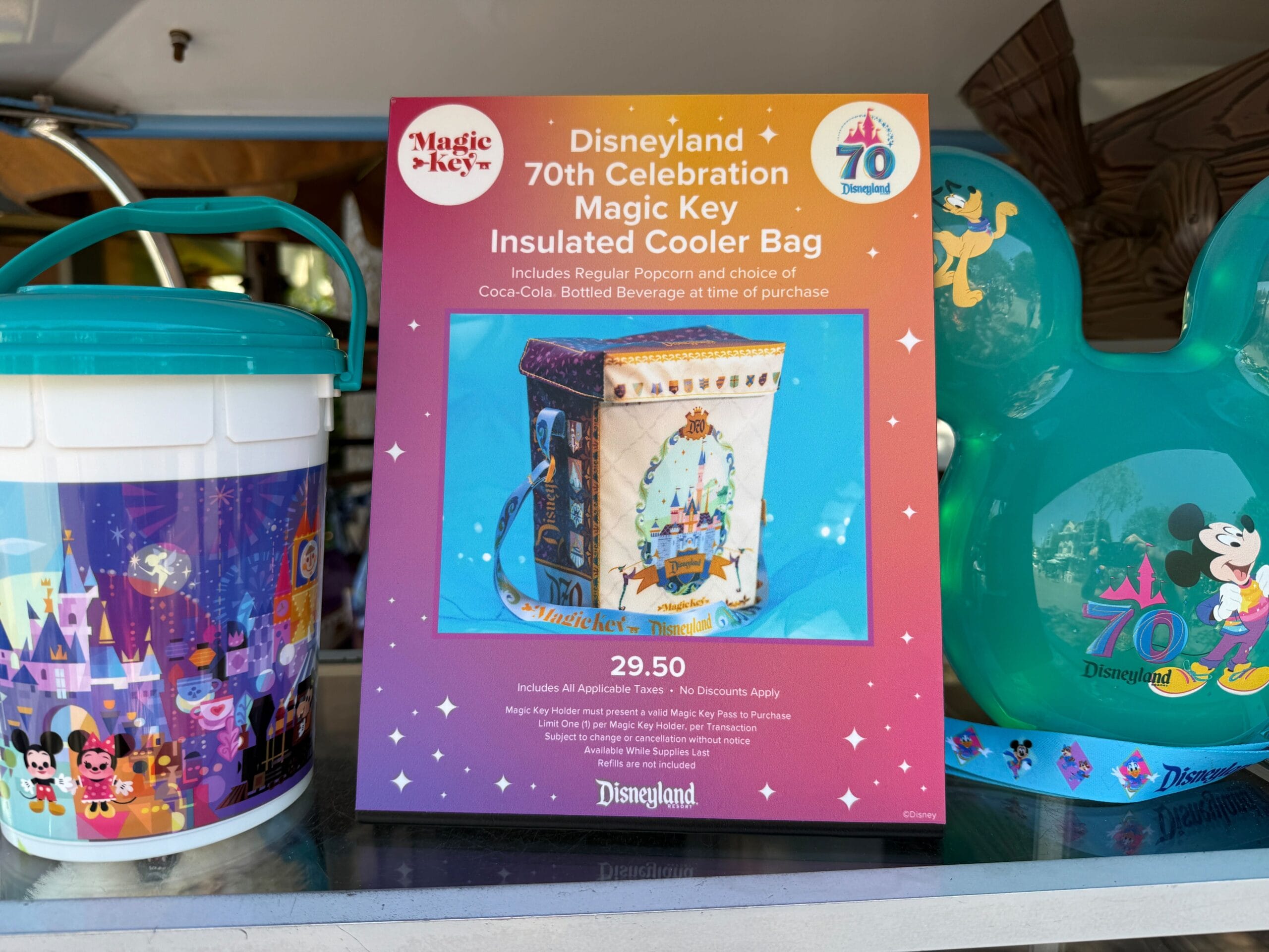 Sign promoting a Disneyland 70th Anniversary Magic Key Exclusive cooler bag with popcorn, drink, and $29.50 price.