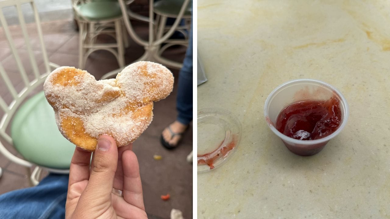 A hand holds a Mickey Mouse-shaped beignet next to a small cup of red jelly and a refreshing mint julep.