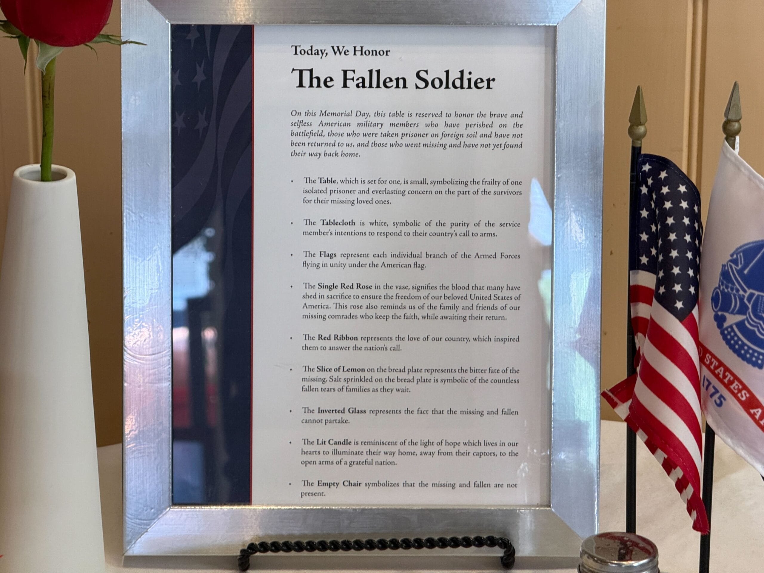 Framed tribute titled "The Fallen Soldier" honors Memorial Day with U.S. flags, red rose, candle, and military insignia.