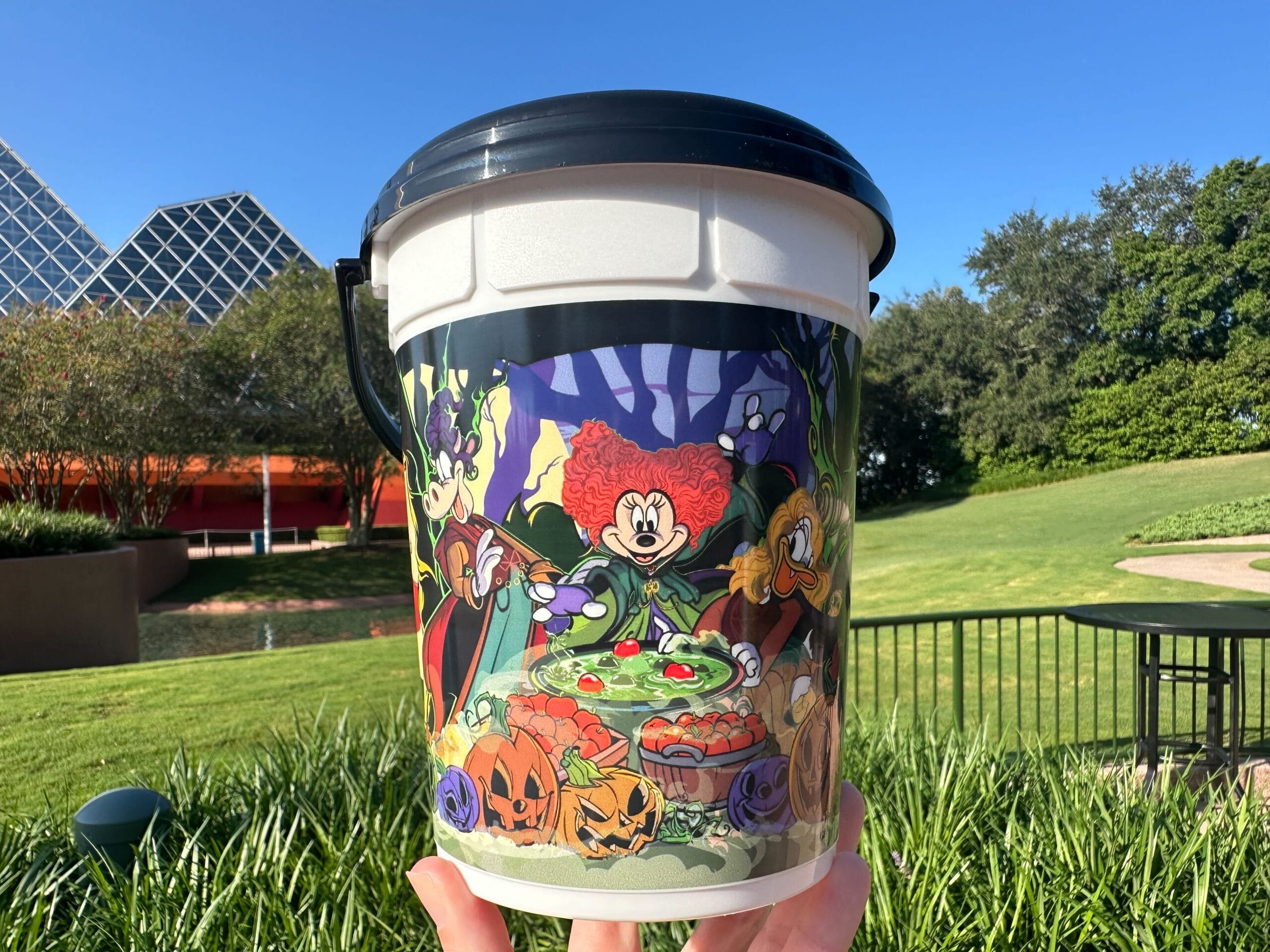 A Disney Popcorn Bucket featuring Mickey, Minnie, and Goofy in witch costumes around a bubbling cauldron.