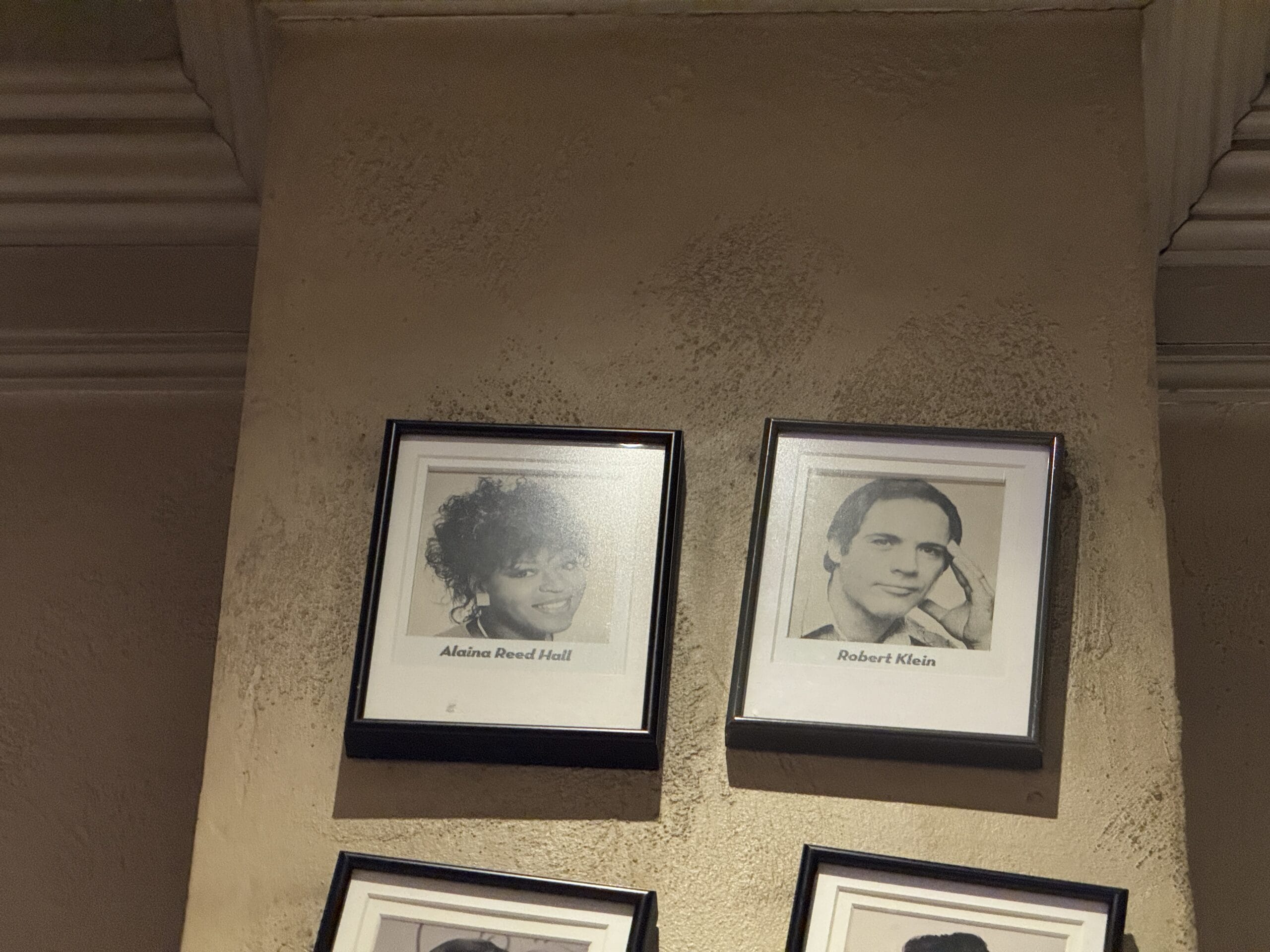 Two black-and-white photos hang on a textured beige wall at Mama Melrose’s Ristorante Italiano in Disney's Hollywood Studios.