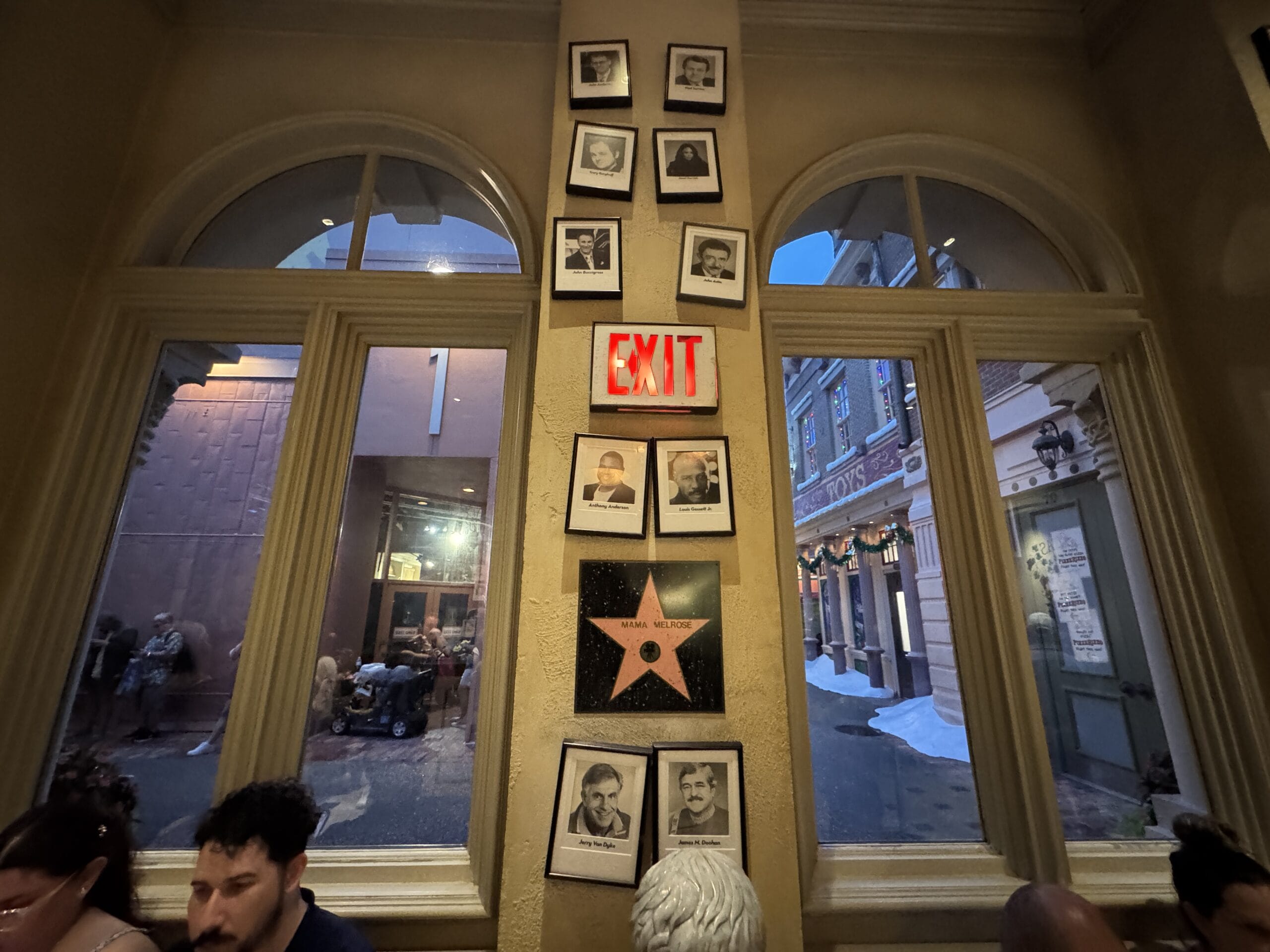 Framed photos and a star plaque above an exit sign at Mama Melrose’s Ristorante Italiano in Disney's Hollywood Studios.