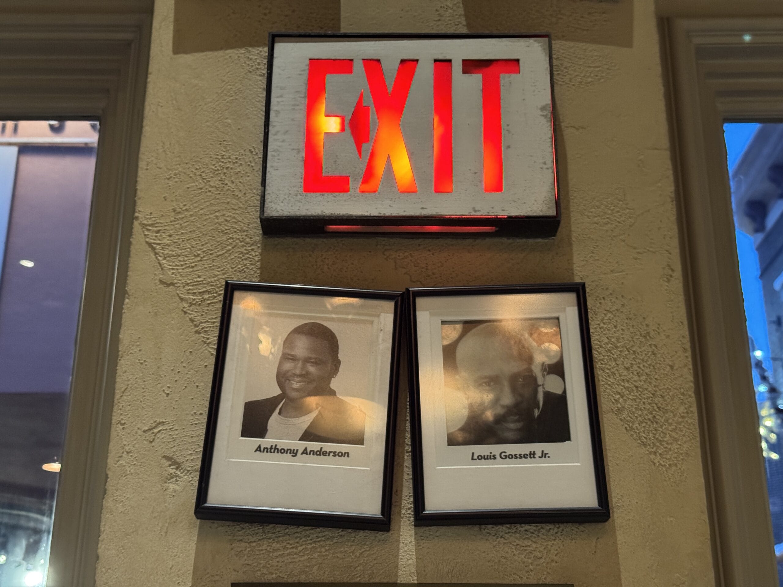 Two framed black-and-white photos under an illuminated EXIT sign at Mama Melrose’s Ristorante Italiano.