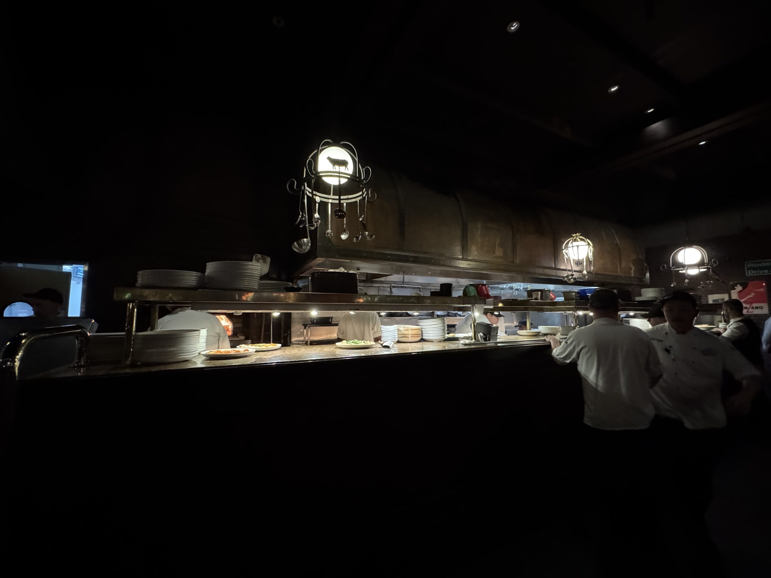 Chefs at Mama Melrose’s Ristorante Italiano prepare plates under warm lights in Disney's Hollywood Studios.
