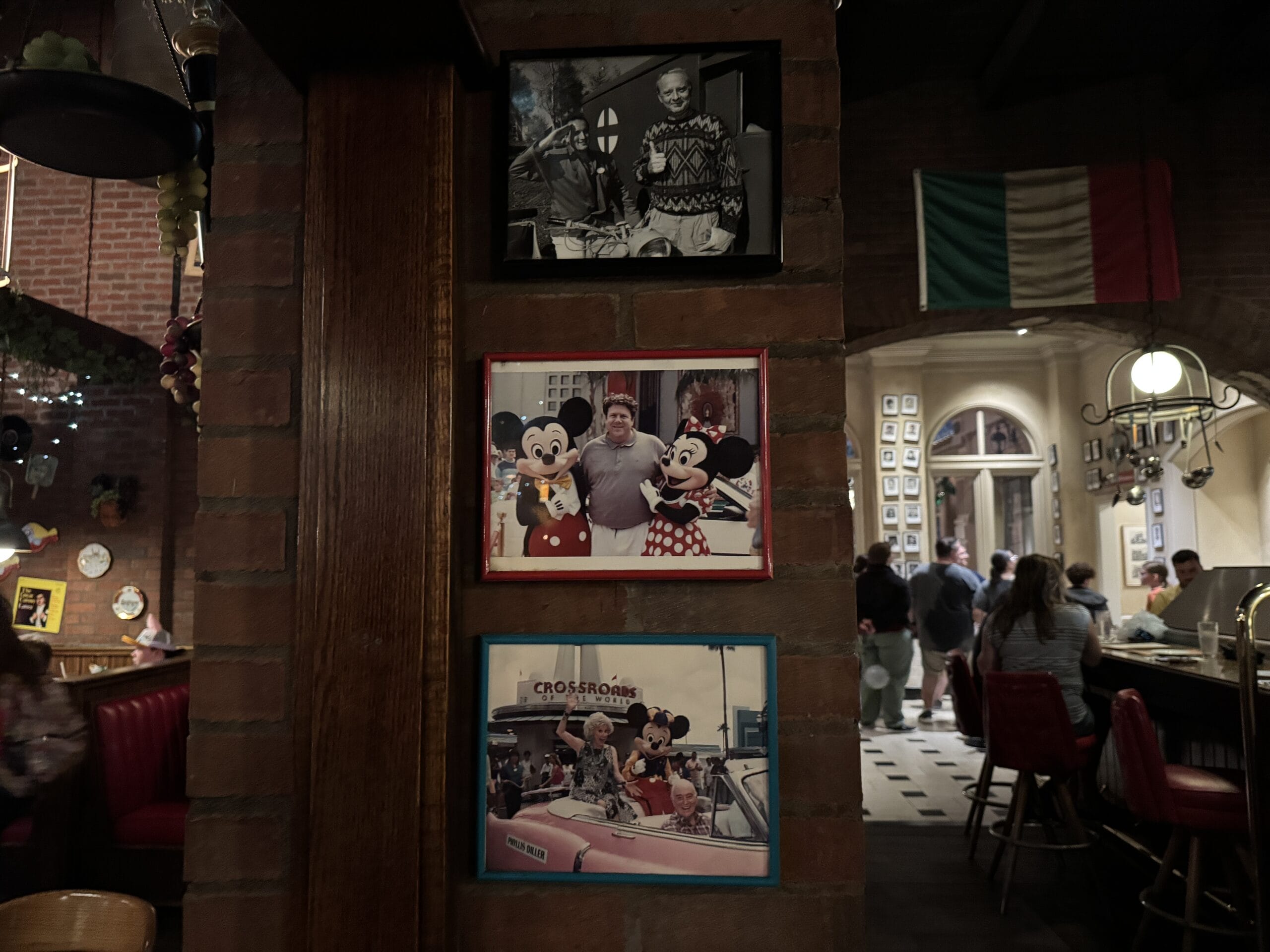 Framed photos of guests with Mickey and Minnie hang on a brick wall inside Mama Melrose’s Ristorante Italiano.