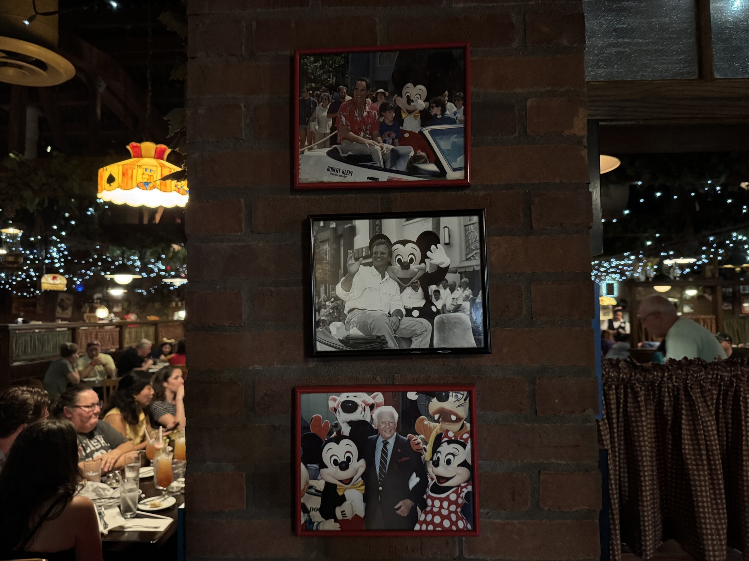 Three framed photos with Disney characters hang on a brick wall at Mama Melrose’s Ristorante Italiano.
