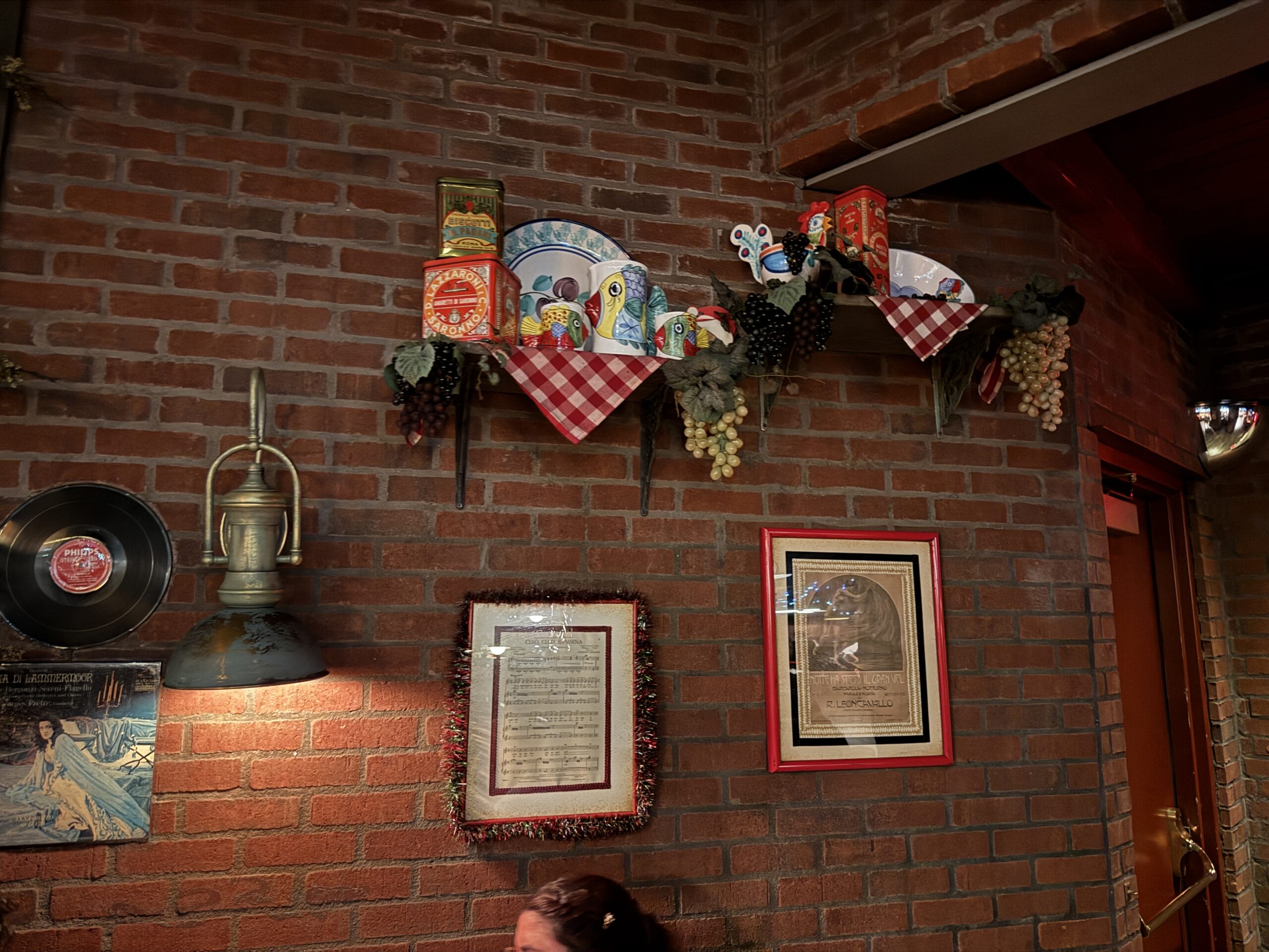 A brick wall at Mama Melrose’s Ristorante Italiano displays plates, tins, grapes, and photos in Disney's Hollywood Studios.