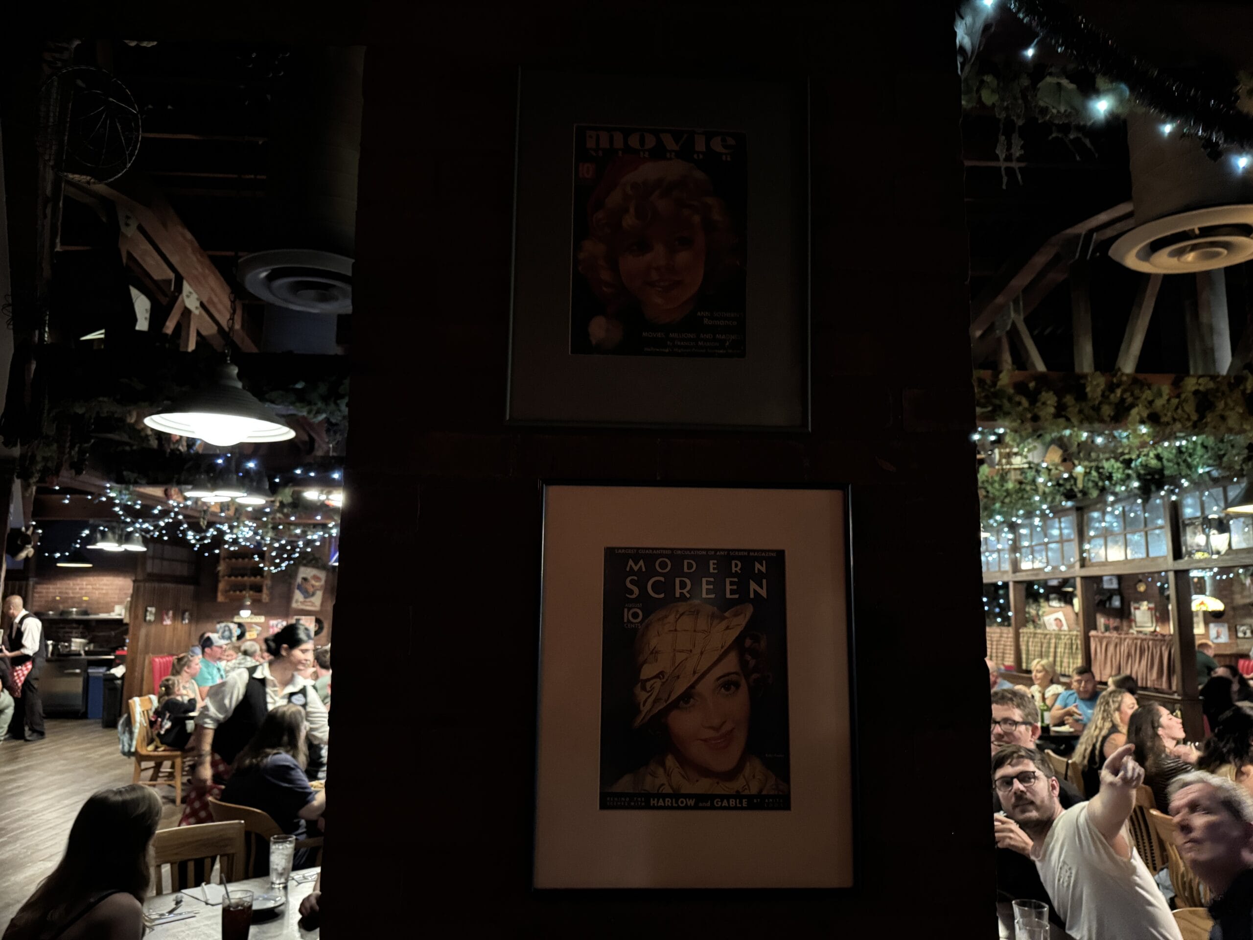A busy restaurant at Disney's Hollywood Studios with vintage photos framed on a dimly lit pillar in the center.