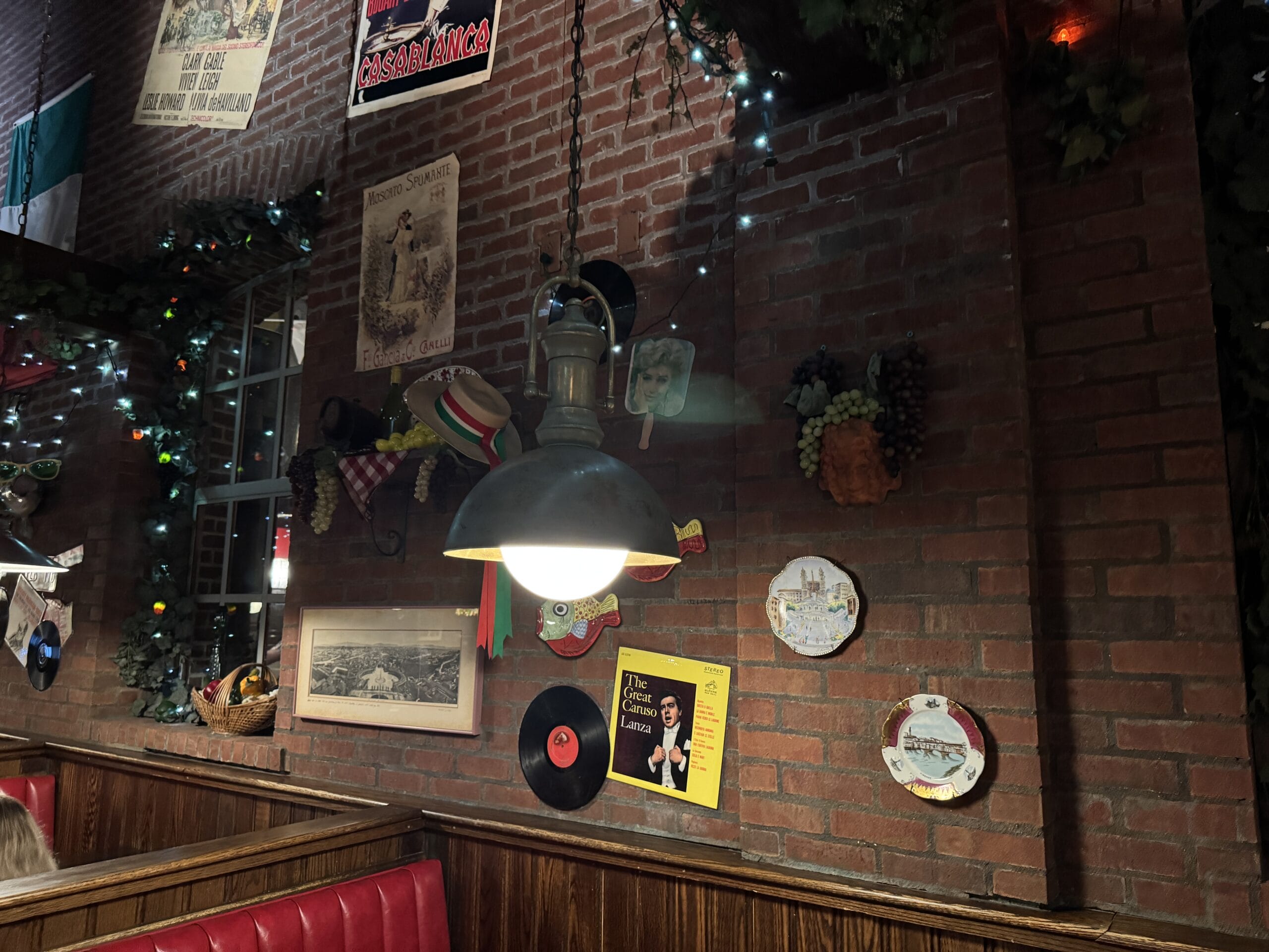 A cozy Mama Melrose’s Ristorante Italiano booth with red seats, vintage decor, and records at Disney's Hollywood Studios.