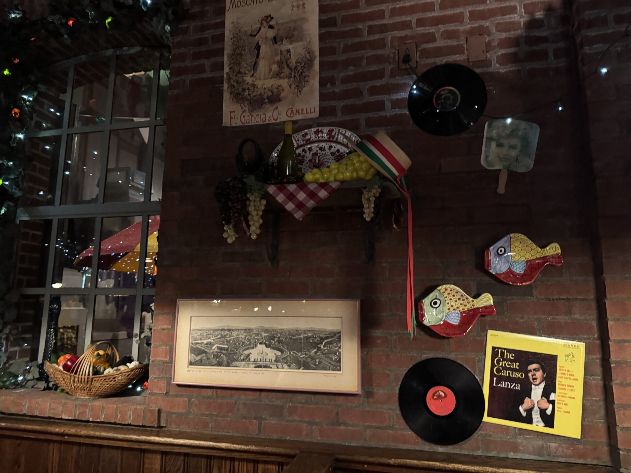 Brick wall at Mama Melrose’s Ristorante Italiano adorned with vinyl records, fish ornaments, and photos in Disney's Hollywood Studios.