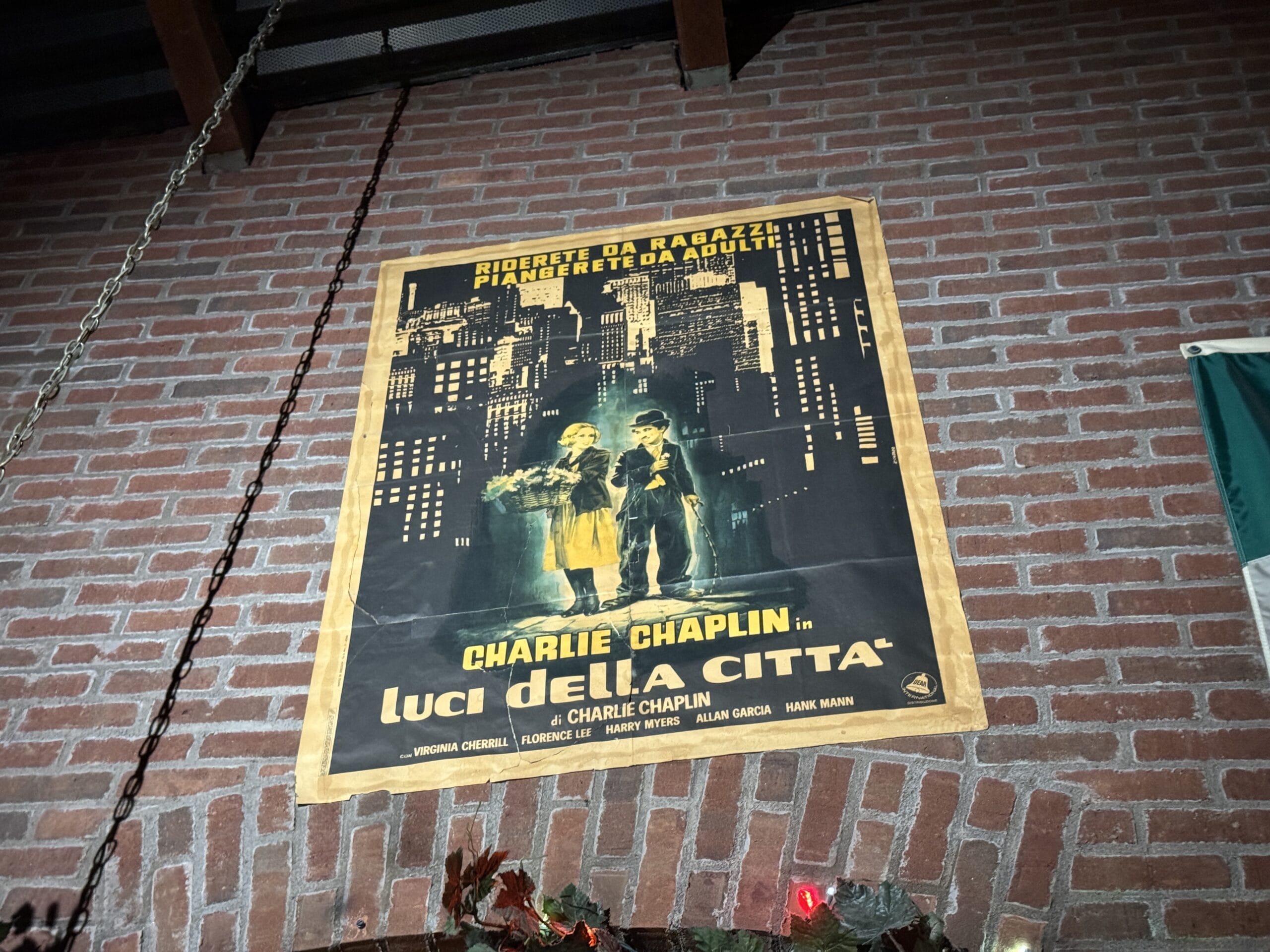 A vintage "Luci della Città" movie poster hangs on a brick wall at Mama Melrose’s Ristorante Italiano.
