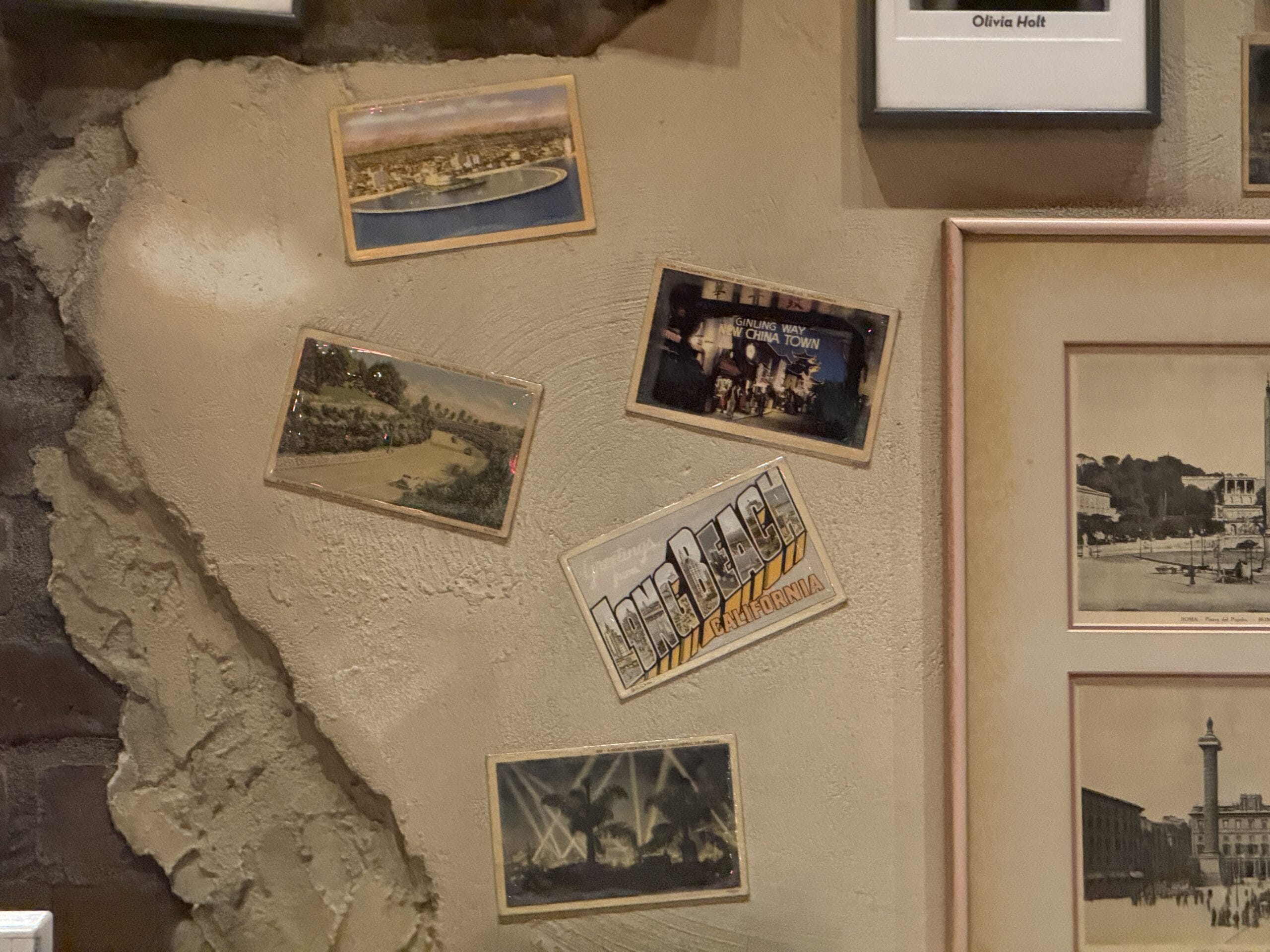 Five vintage postcards and photos are displayed on a textured beige wall at Mama Melrose’s Ristorante Italiano.