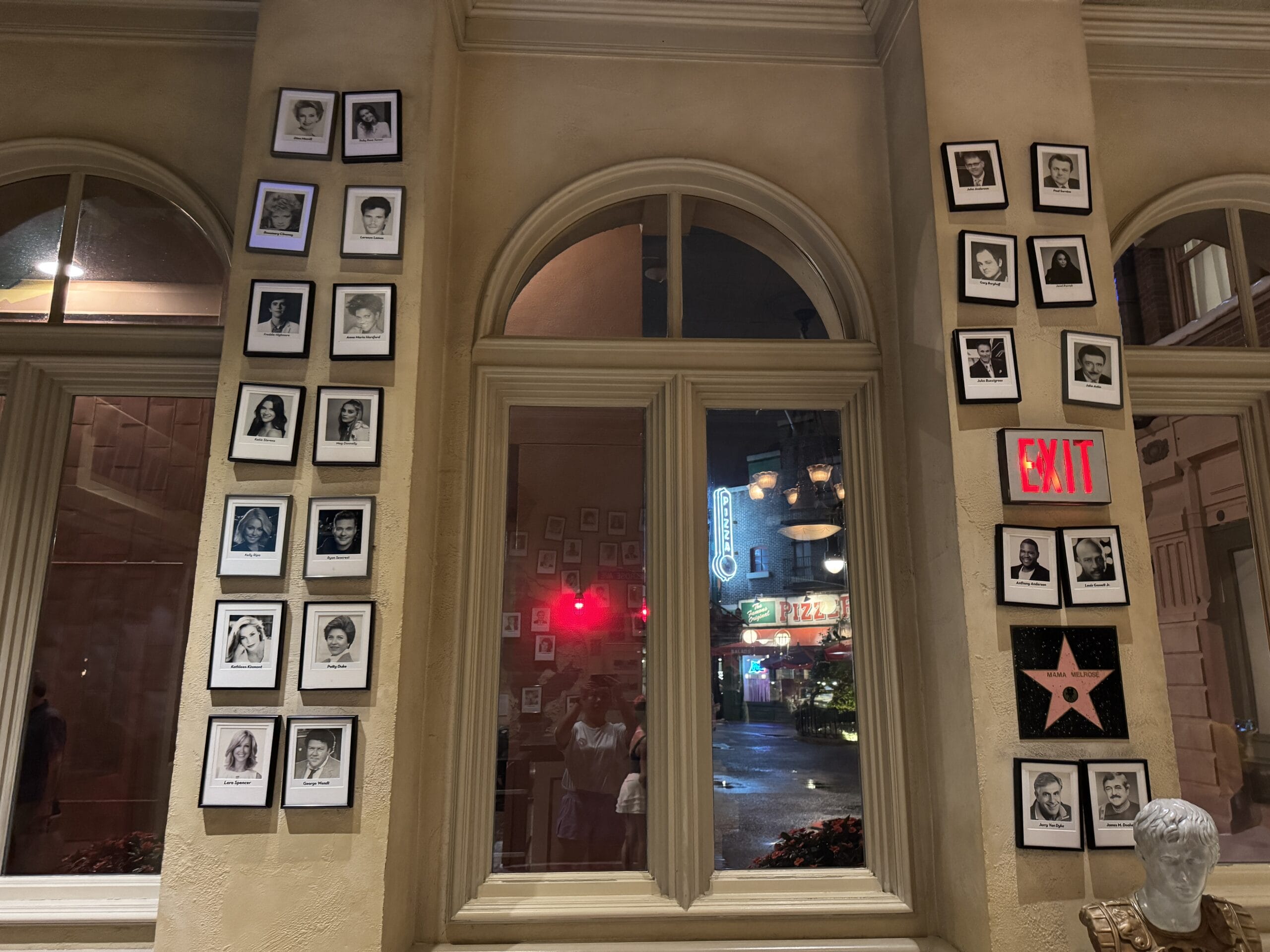 Framed black-and-white photos line the walls by large windows at night inside Mama Melrose’s Ristorante Italiano.