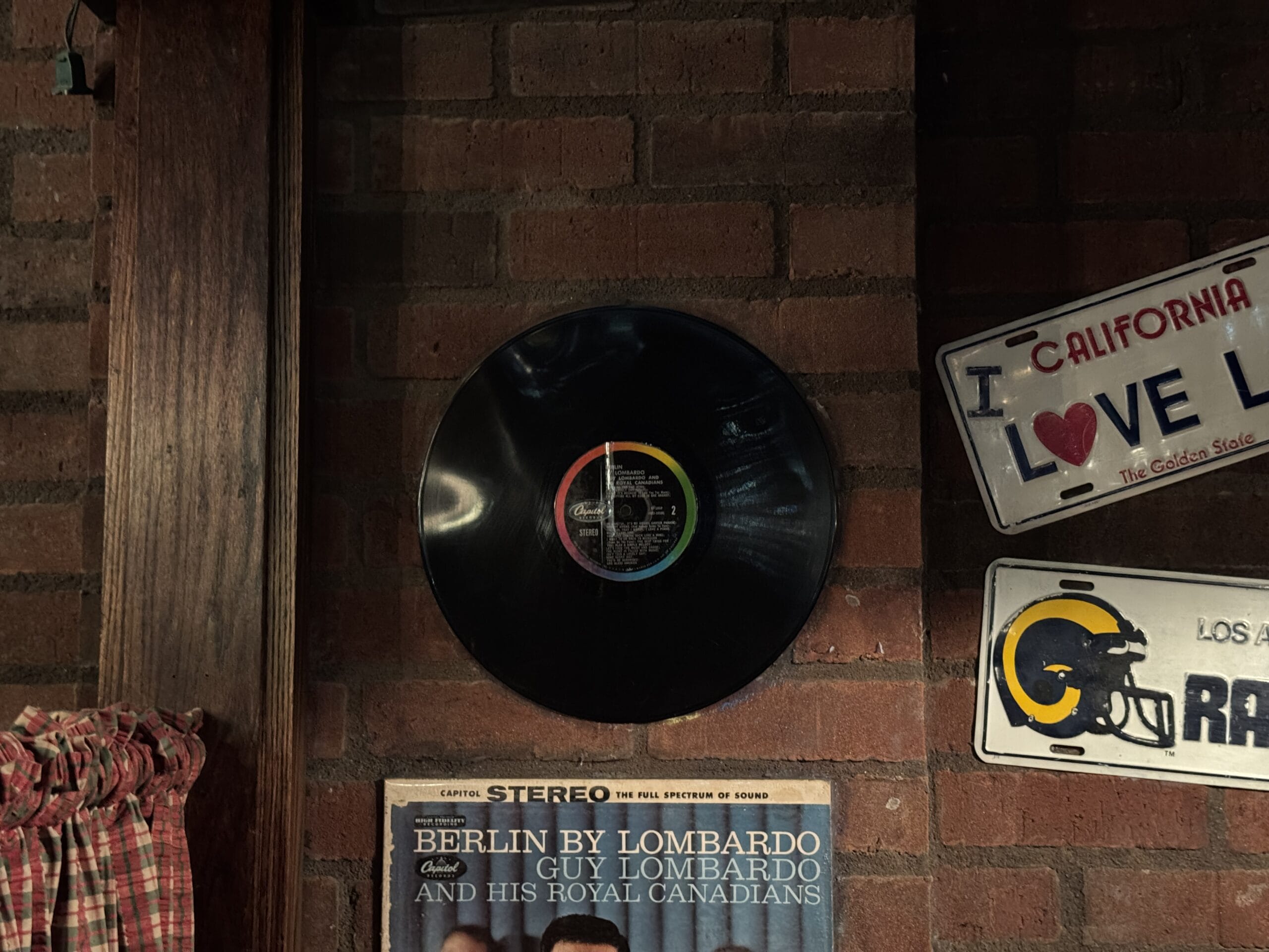 A vinyl record is mounted on a brick wall at Mama Melrose’s Ristorante Italiano, surrounded by vintage photos and posters.