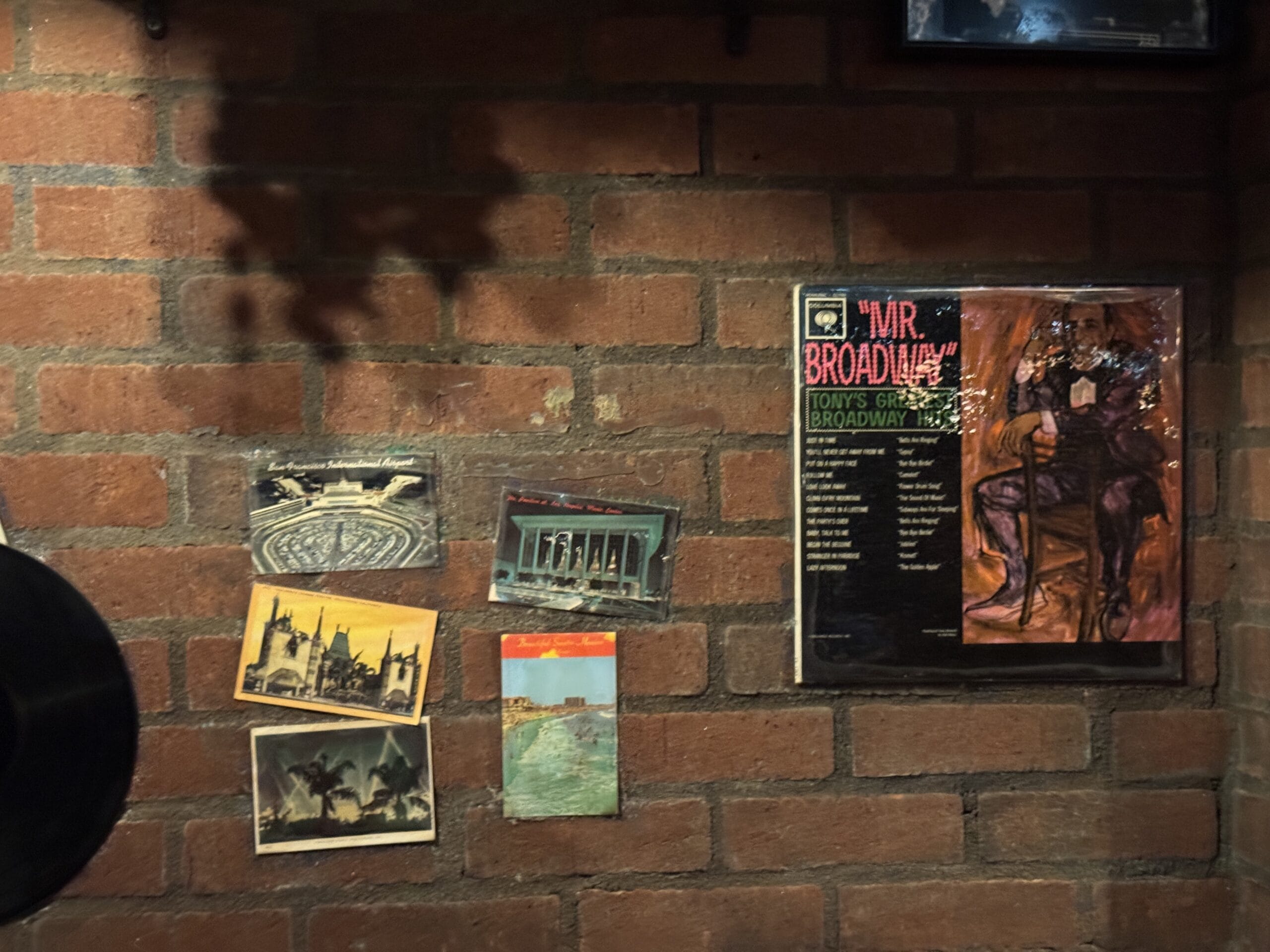 Postcards and photos line a brick wall at Mama Melrose’s Ristorante Italiano in Disney's Hollywood Studios.