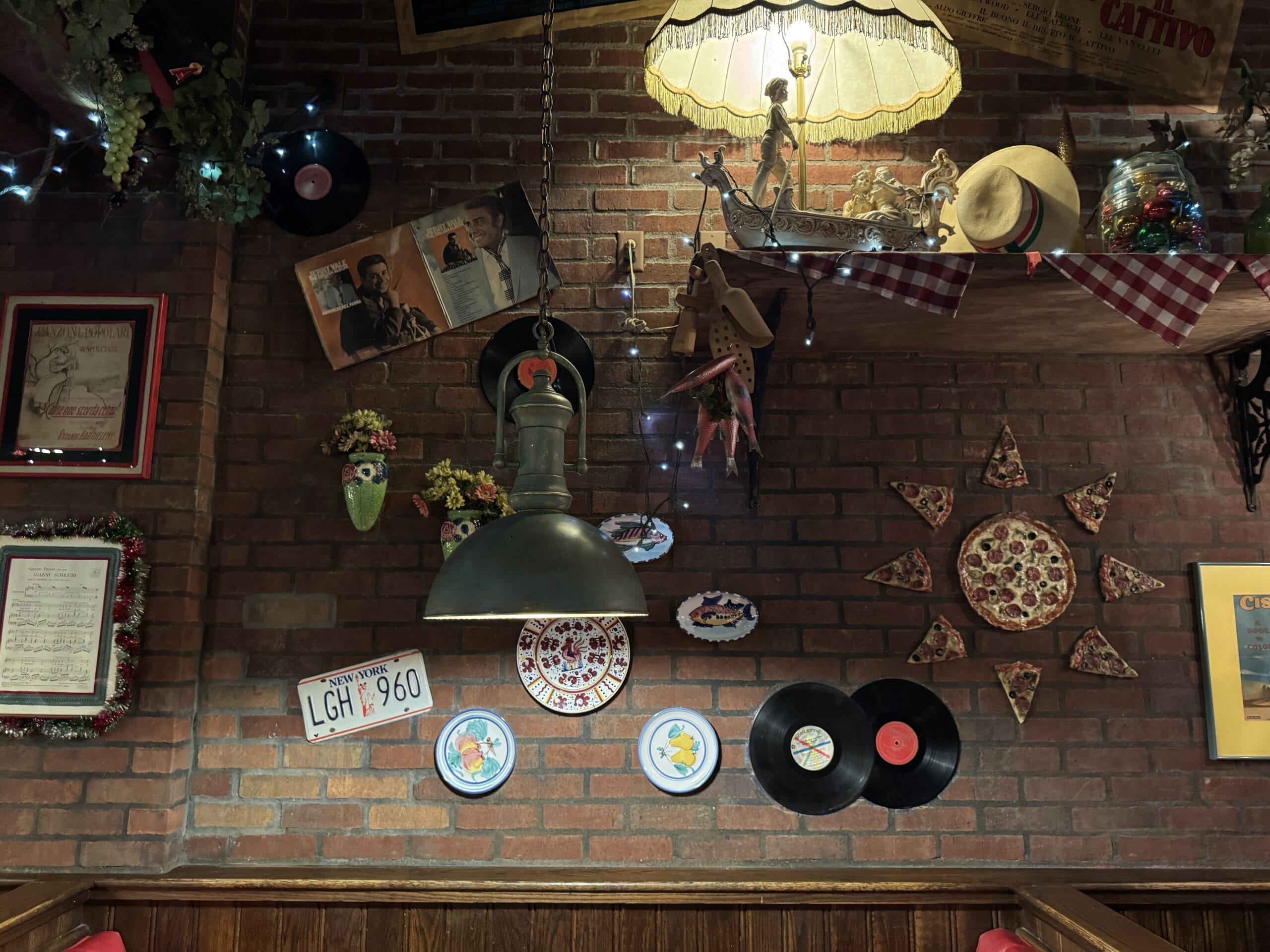 Brick wall at Mama Melrose’s Ristorante Italiano adorned with records, pizza slices, photos, flowers, and vintage memorabilia.
