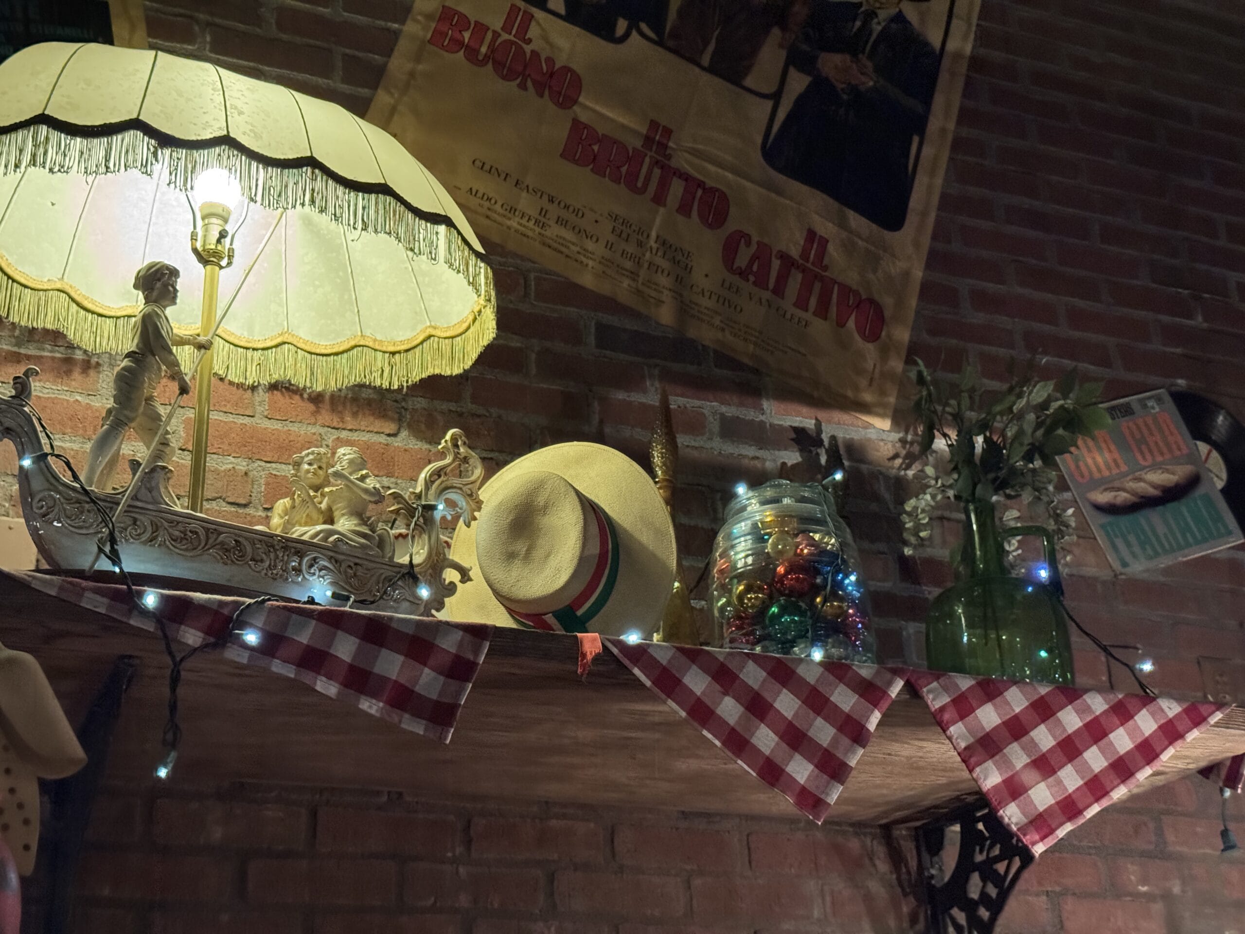 A cozy shelf at Mama Melrose’s Ristorante Italiano, perfect for photos, glows with string lights and decor against the brick wall.
