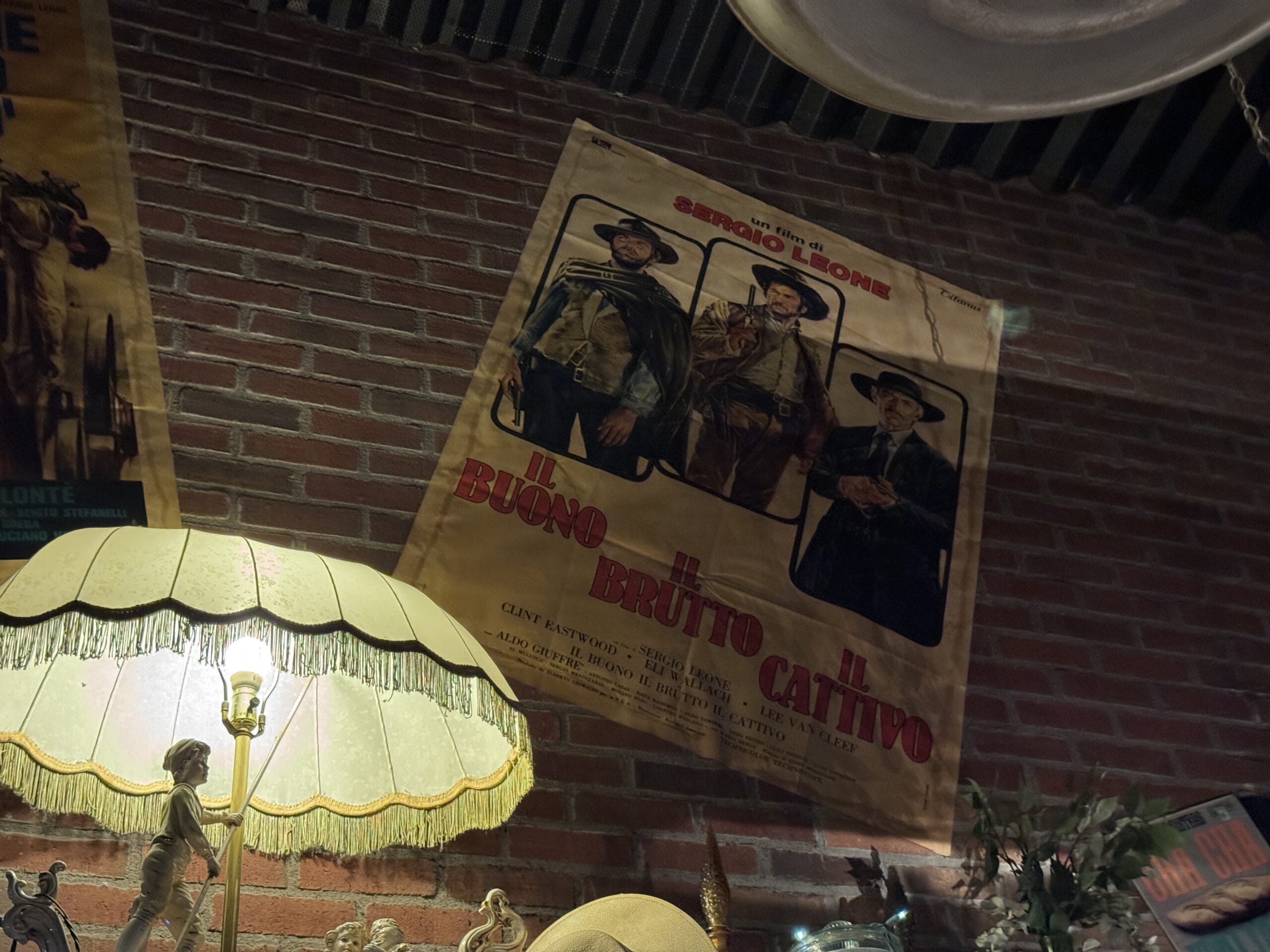 A vintage movie poster hangs on a brick wall above a lit lamp at Mama Melrose’s Ristorante Italiano in Disney's Hollywood Studios.