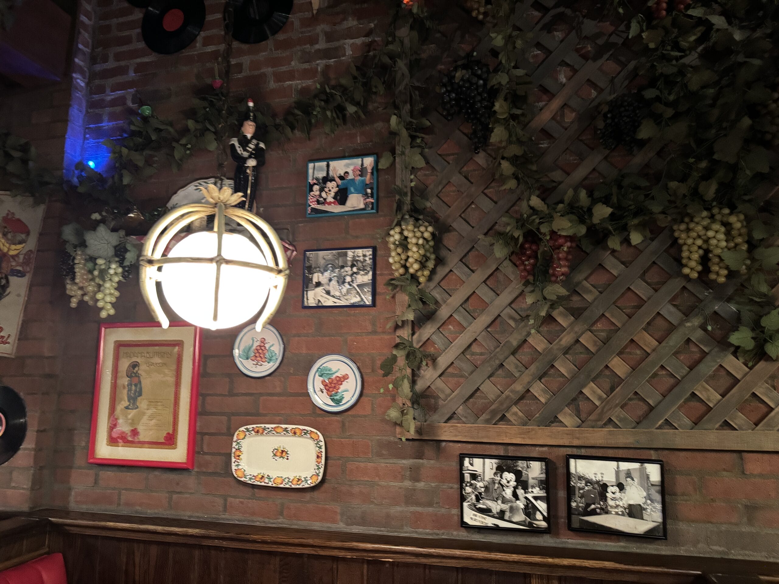 Wall decorated with framed photos and plates at Mama Melrose’s Ristorante Italiano, a cozy, vintage-themed restaurant.