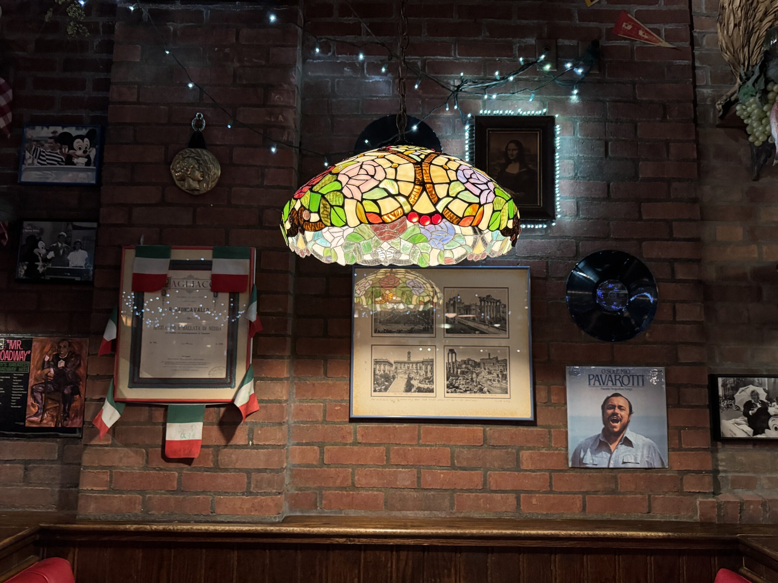A stained-glass lamp hangs on a brick wall at Mama Melrose’s Ristorante Italiano in Disney's Hollywood Studios.