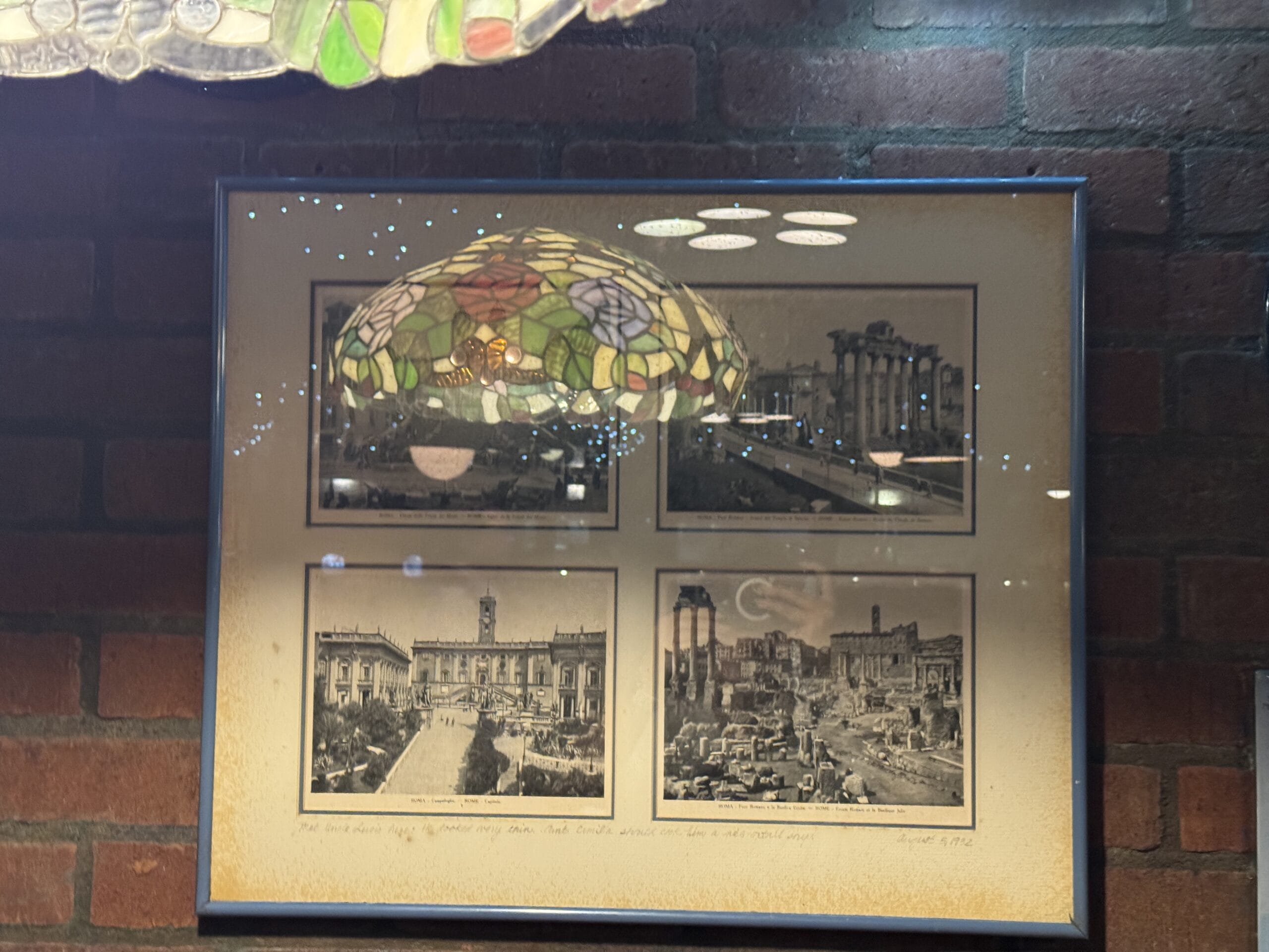 Framed vintage black-and-white photos at Mama Melrose’s Ristorante Italiano reflect a stained glass lamp above.