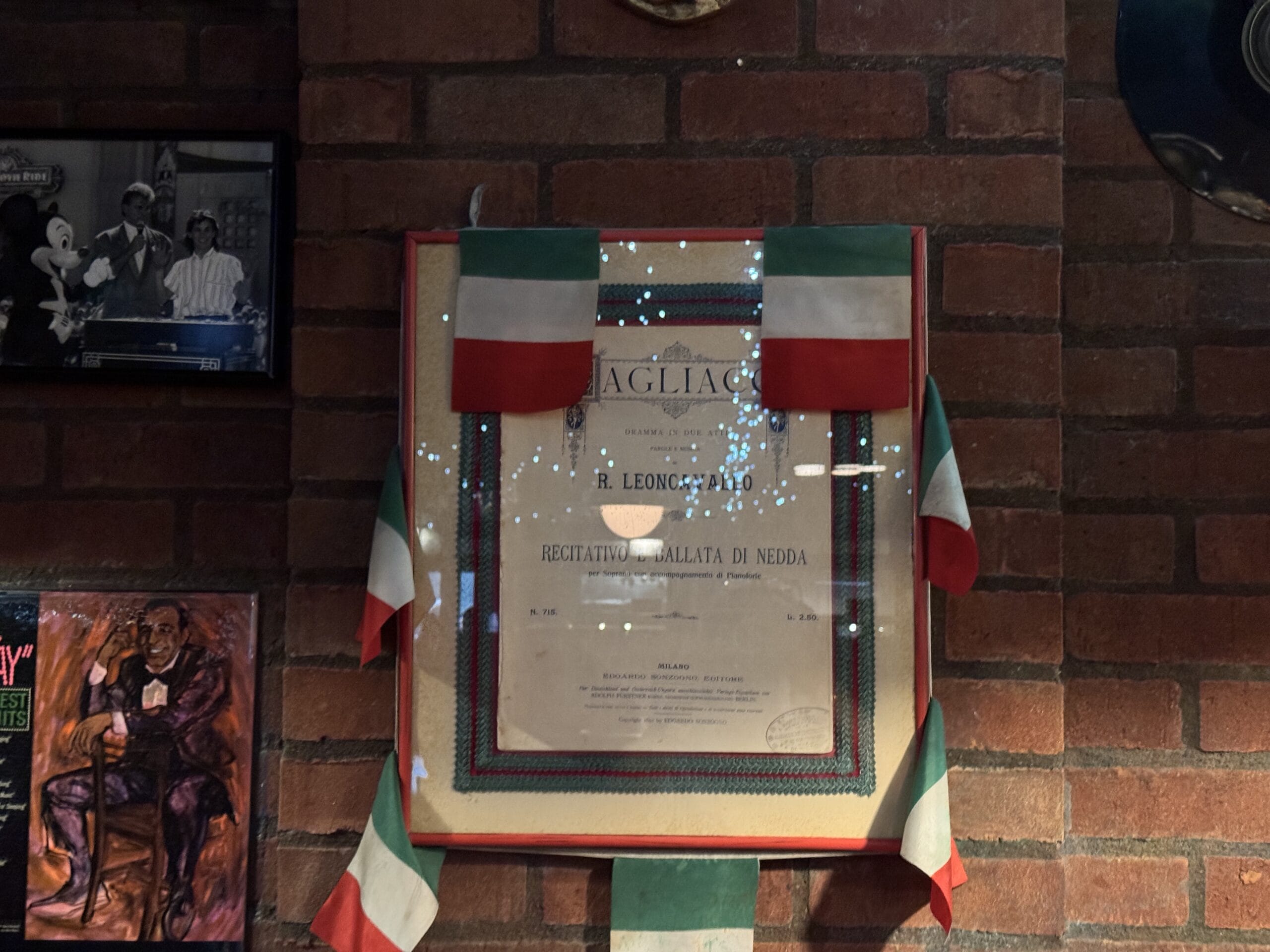 A framed certificate at Mama Melrose’s Ristorante Italiano hangs on a brick wall, surrounded by photos and Italian flags.