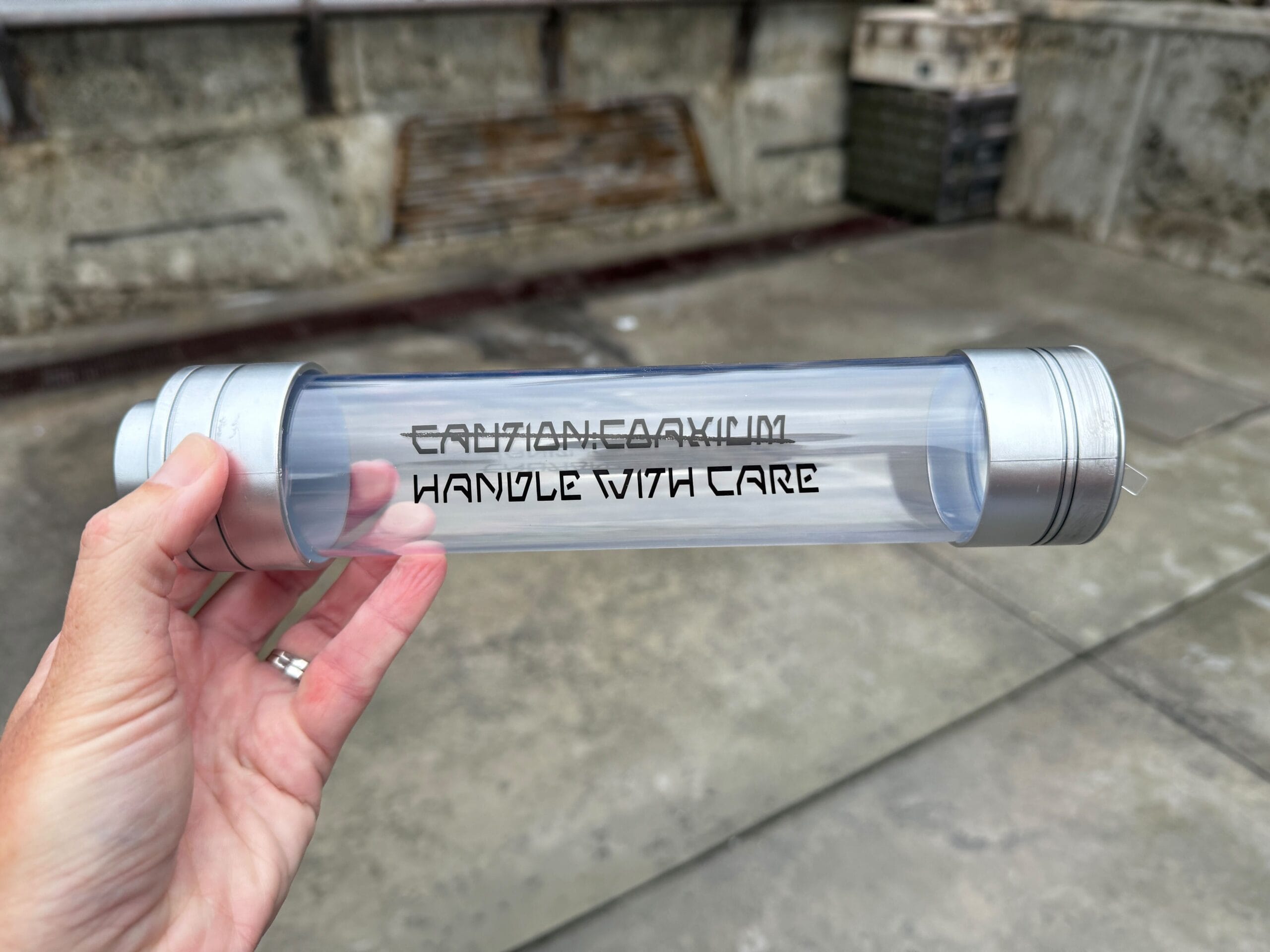 A hand holds a Coaxium Sipper labeled "FRAGILE: CAUTION HANDLE WITH CARE," perfect for Star Wars Day fans.