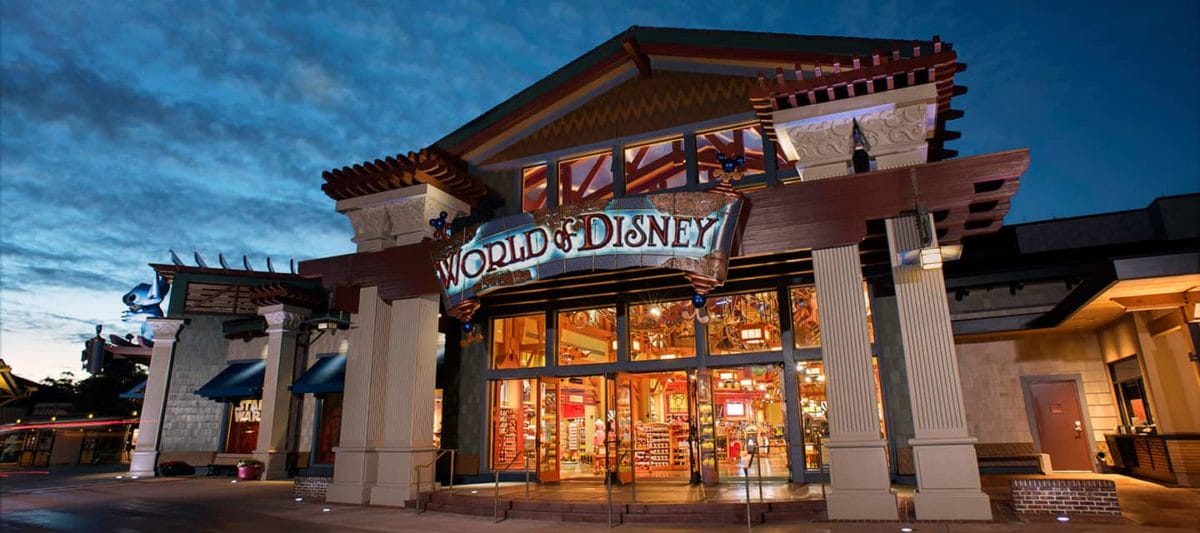 The entrance of the World of Disney store at dusk, brightly lit near Disney World with colorful displays in large windows.