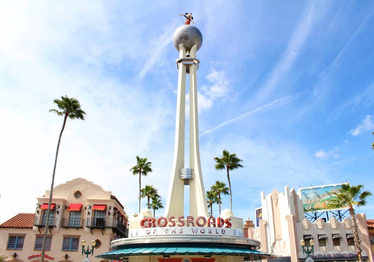 A tall white tower with a globe and figure on top in Florida reads "Crossroads of the World" at Hollywood Studios Disney World