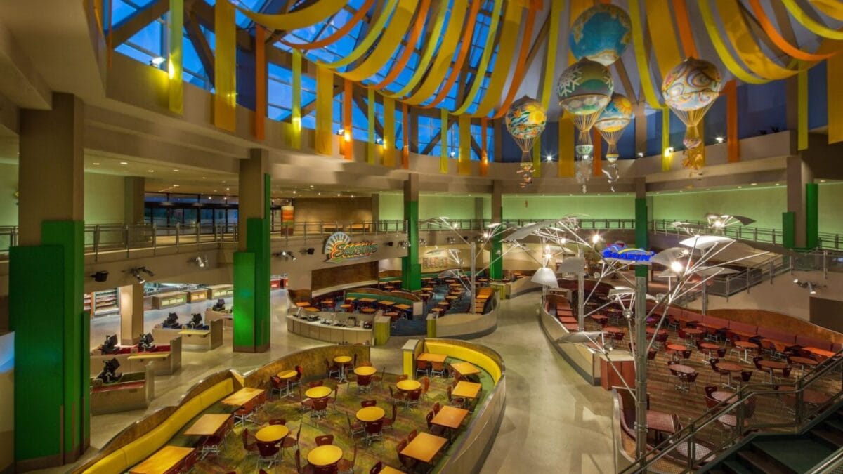 Spacious, colorful cafeteria with round tables and booths—perfect for dining at sunshine seasons EPCOT under a glass dome ceiling.
