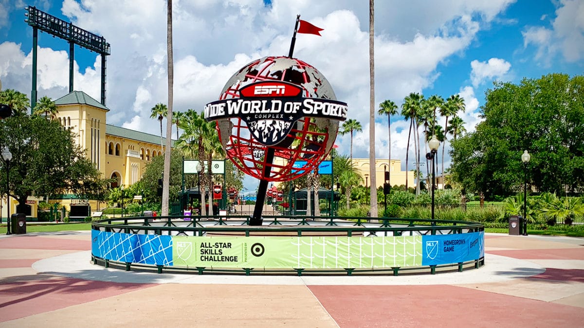 The ESPN Wide World of Sports globe stands before palm trees at Disney World under Orlando’s bright blue sky.