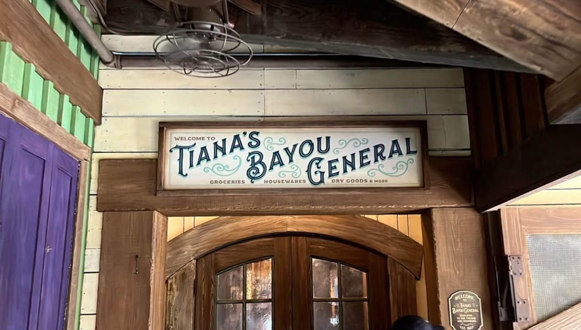Sign above double doors in Frontierland reads “Tiana’s Bayou General—Groceries, Housewares, Dry Goods & More.”