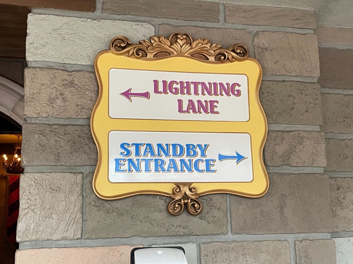 A decorative sign with arrows shows Lightning Lane Multi Pass left and Standby Entrance to the right.