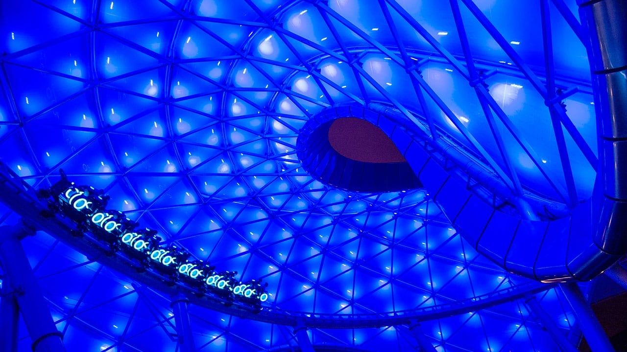 Geometric, dome-like ceiling at Magic Kingdom, lit with blue lights and triangle patterns, spiral opening at the center.