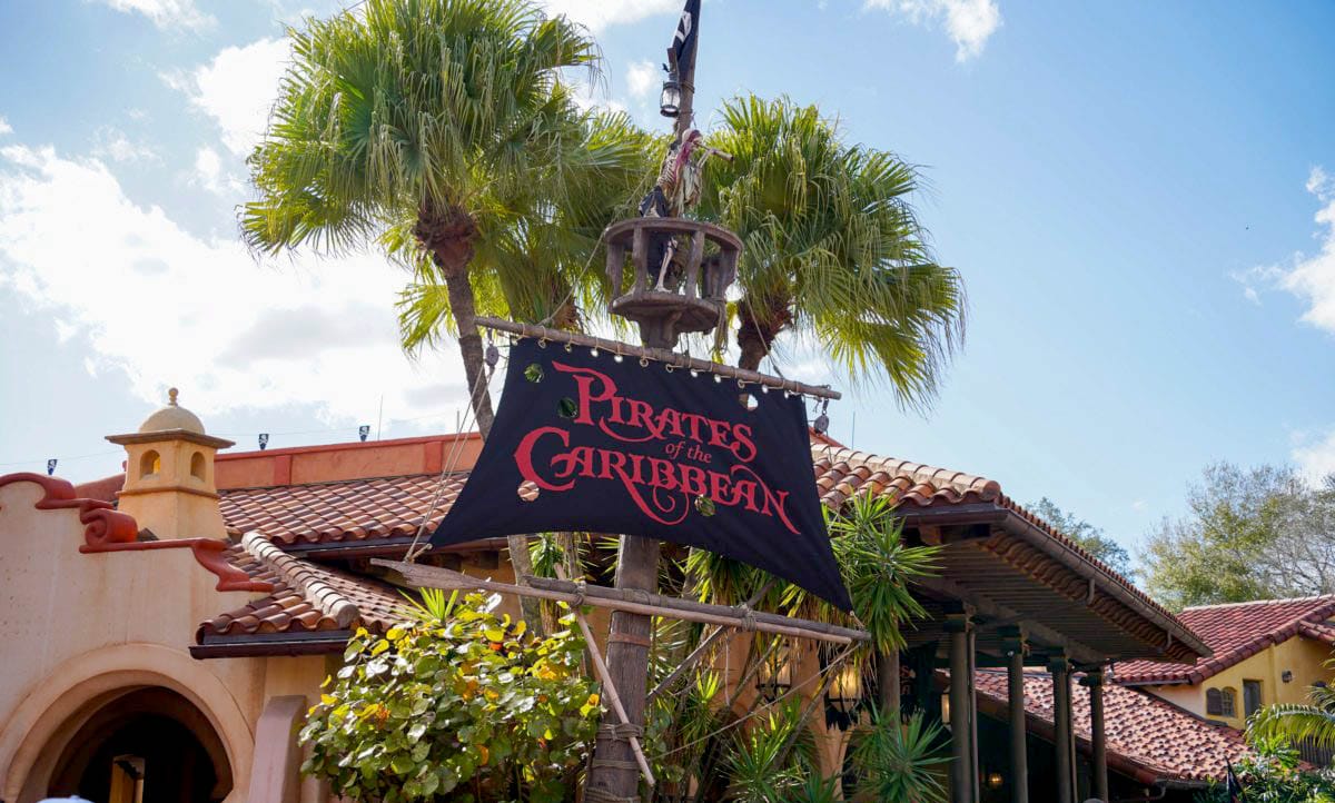 A "Pirates of the Caribbean" sign hangs by palm trees at Magic Kingdom in Walt Disney World.