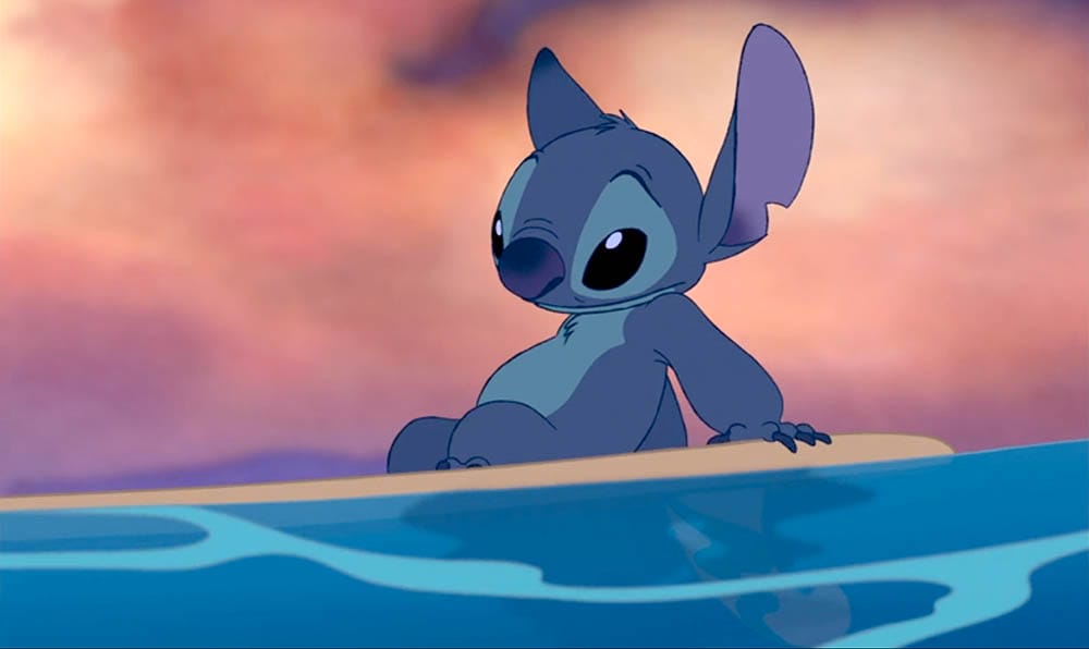 Animated blue alien Stitch sits on a surfboard in the water, perfect as a Stitch Wallpaper for Free Downloads.
