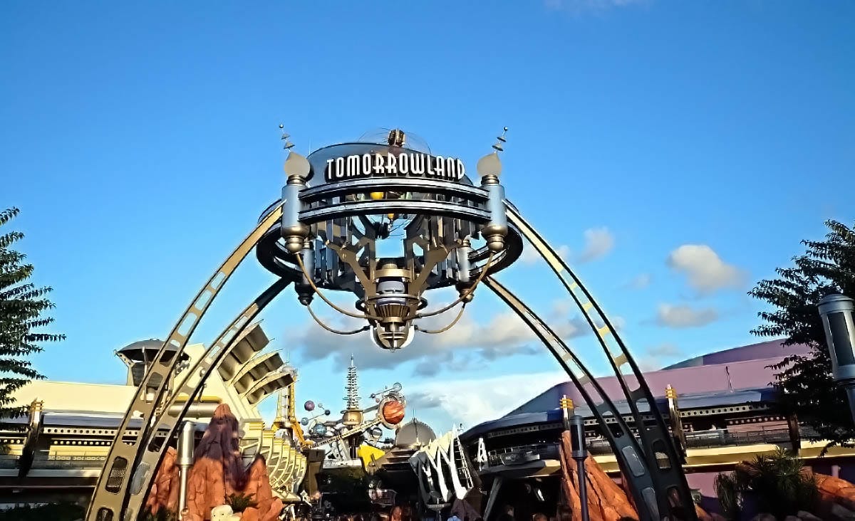 Tomorrowland entrance arch with a metallic futuristic design welcomes you under the bright blue Tomorrowland sky. Tomorrowland entrance arch with a metallic futuristic design welcomes you under the bright blue Tomorrowland sky.