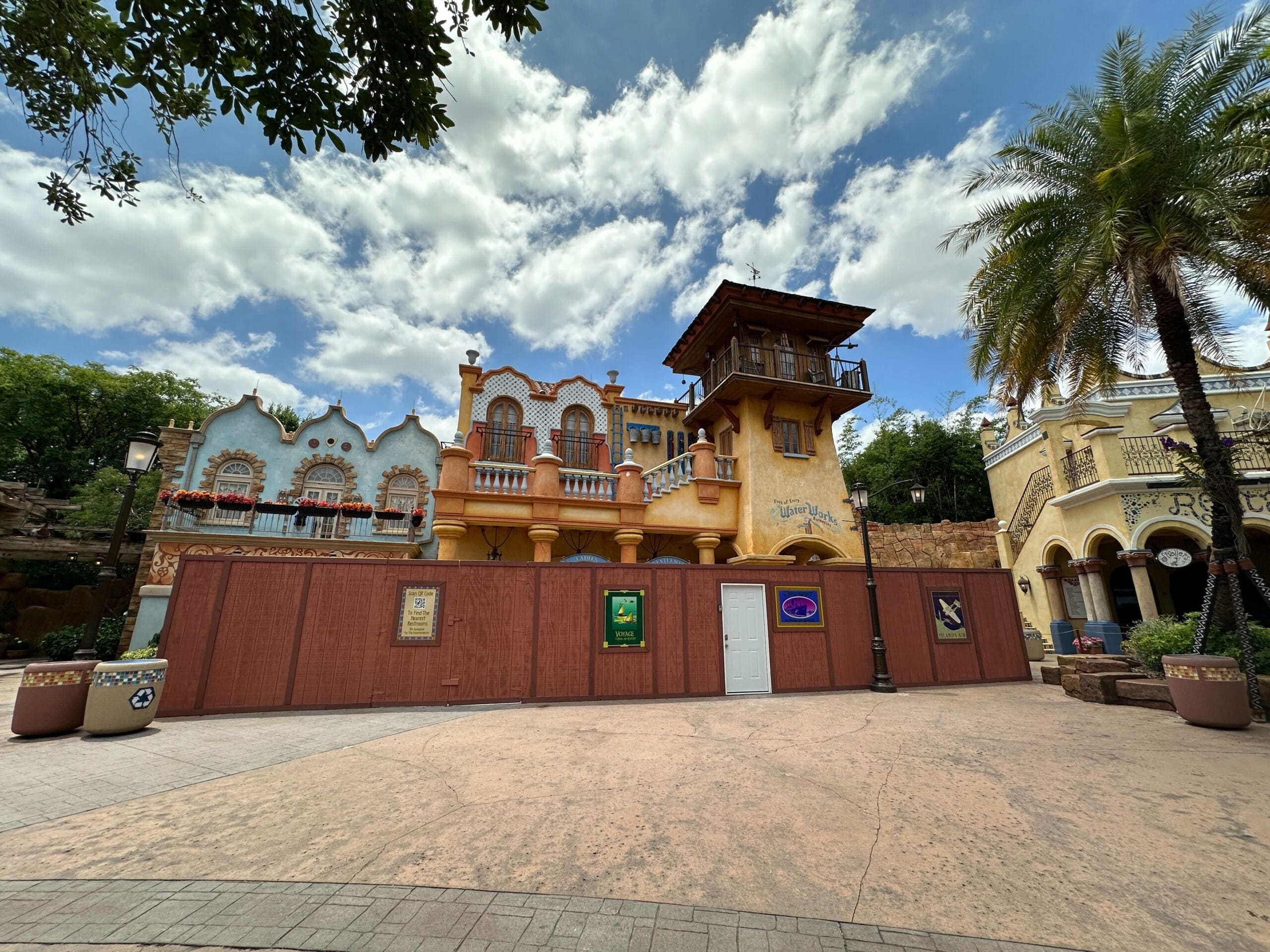 A colorful building by the entrance at Universal Islands of Adventure, behind a fence for restrooms refurbishment on a sunny day.