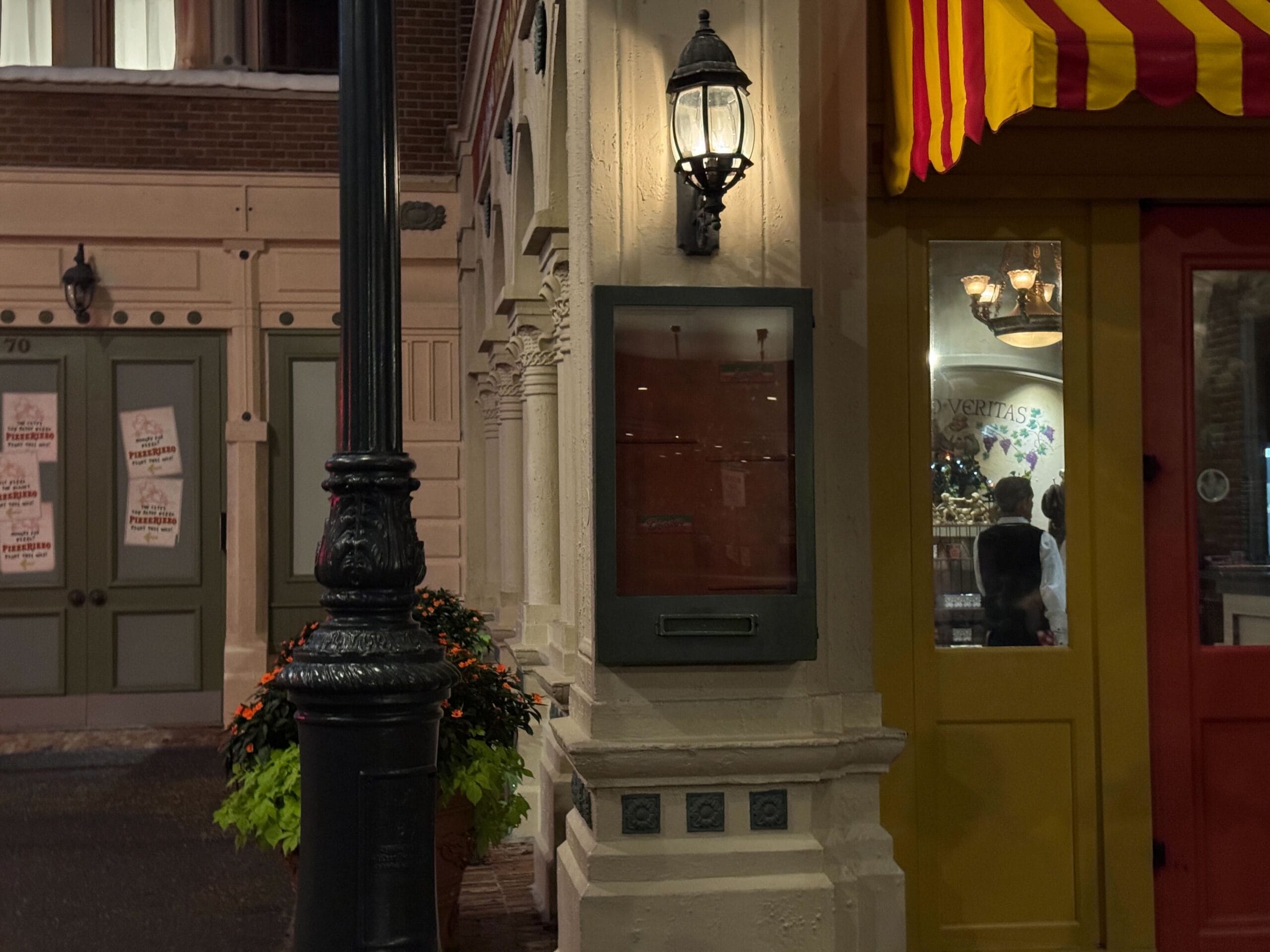 Nighttime street view of Mama Melrose’s Ristorante Italiano, restaurant closed, with a lit lantern and striped awning.