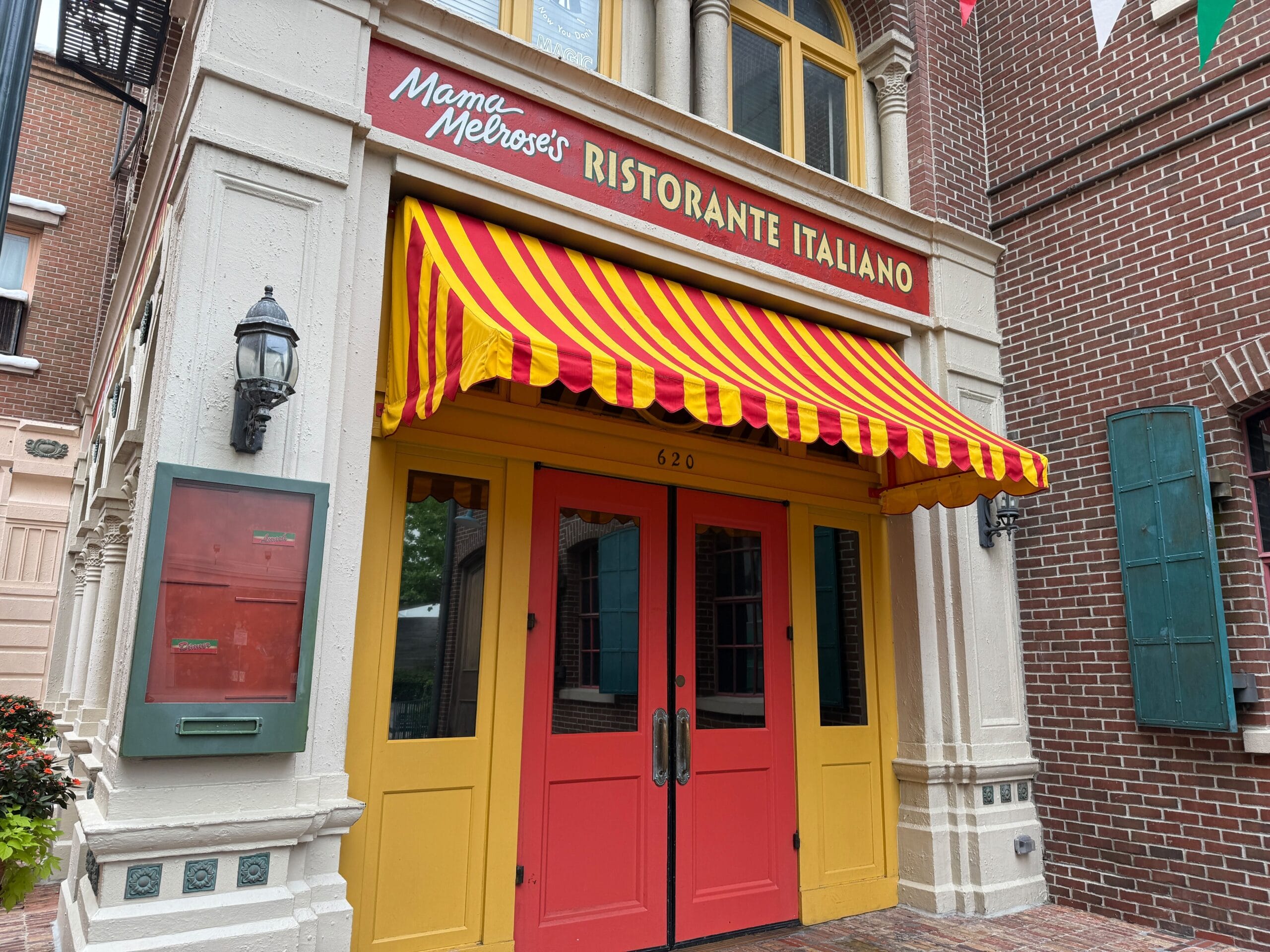 Entrance of Mama Melrose’s Ristorante Italiano at Disney's Hollywood Studios, with red doors and a striped awning.
