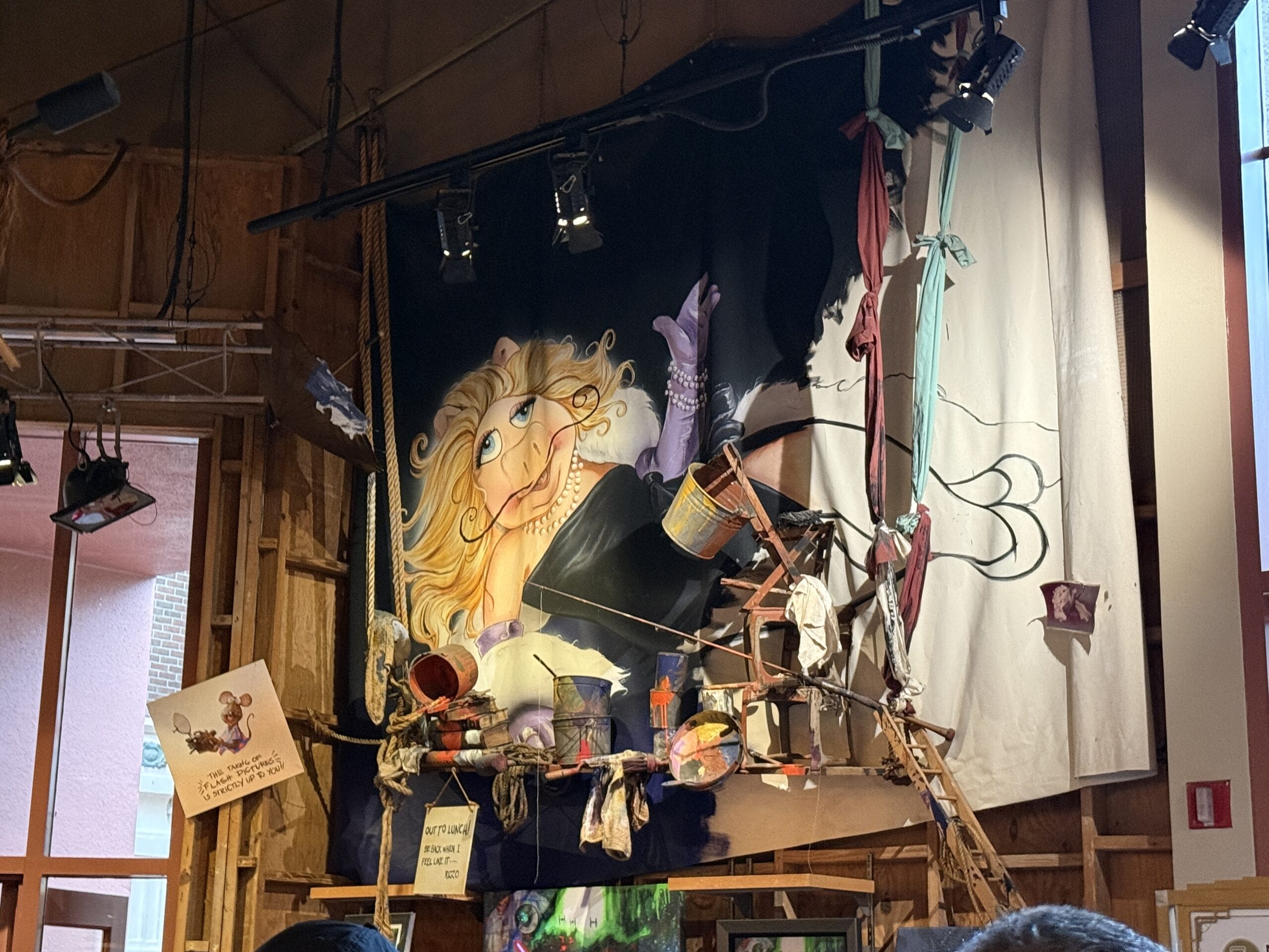 Colorful mural of a blonde woman with purple gloves, seen indoors at the Hollywood Studios Muppet Store.