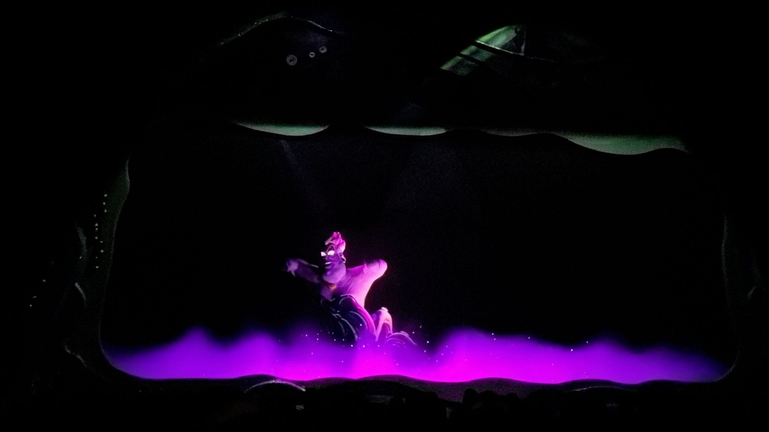 A purple sea witch animatronic rises from glowing purple fog in Little Mermaid: A Musical Adventure.