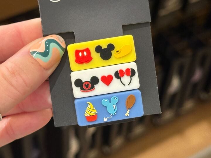 Three colorful pins with Disney-themed icons, including Mickey ears, a hat, heart, Minnie bow, ice cream, and turkey leg.