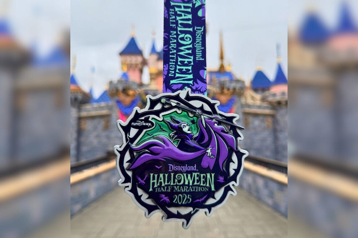 A Disneyland Halloween Half Marathon 2025 finisher medal with Maleficent, displayed before Sleeping Beauty Castle.