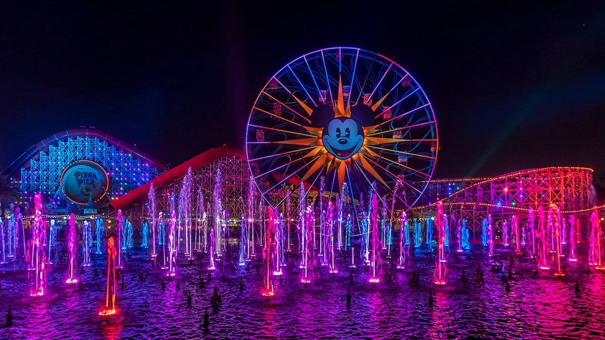 Colorful fountains and a Mickey Ferris wheel light up the night at Disneyland—see how it compares in our Disney World comparison guide.