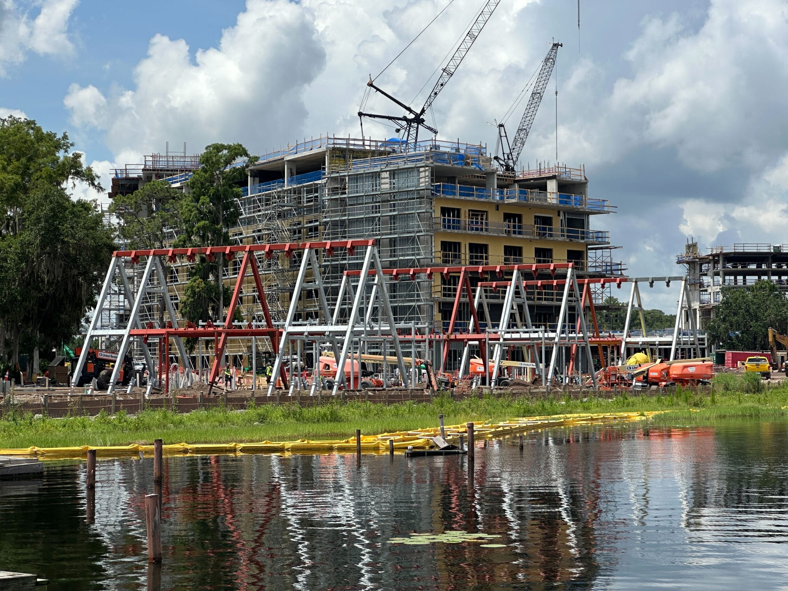 Lakeshore Lodge Construction: A hotel rises with cranes and steel framing near the water on a partly cloudy day.