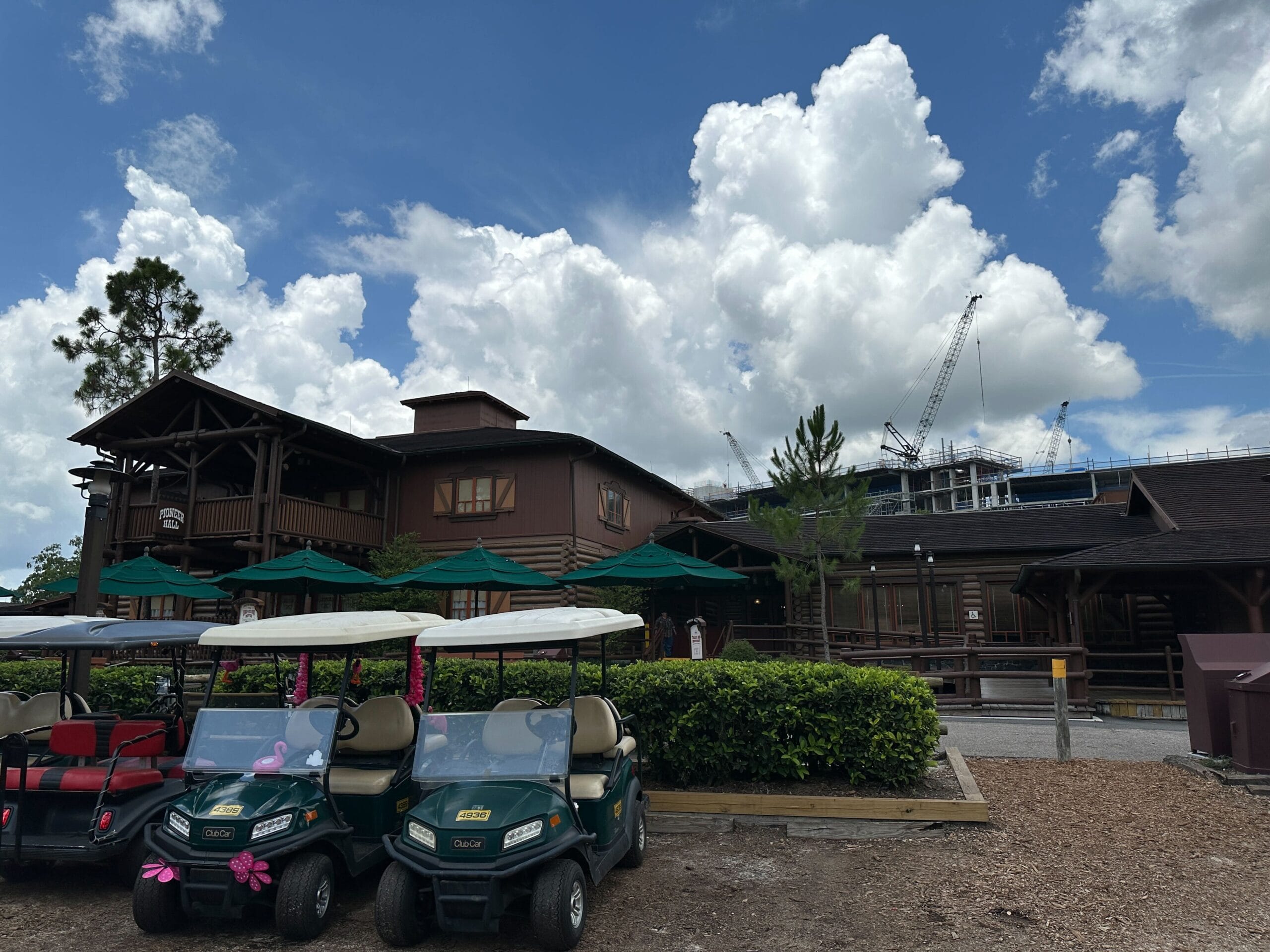Brown lodge-style building with green golf carts in front; Lakeshore Lodge construction cranes visible in the background.