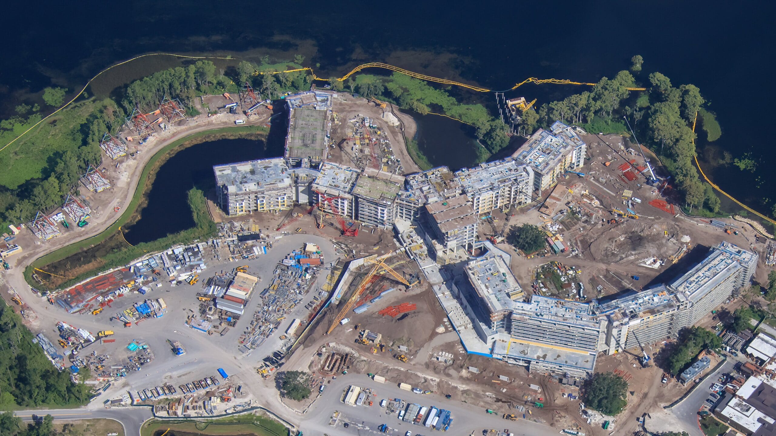 Aerial view of Lakeshore Lodge construction site with multiple buildings near water and lush greenery.
