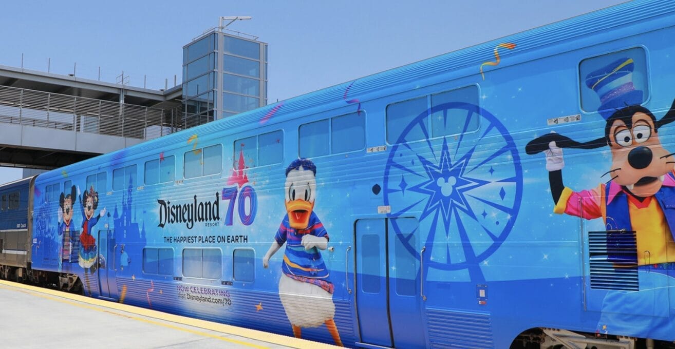 Blue train with Disneyland 70th anniversary design, a summer offering featuring Goofy and Donald, parked at a station.